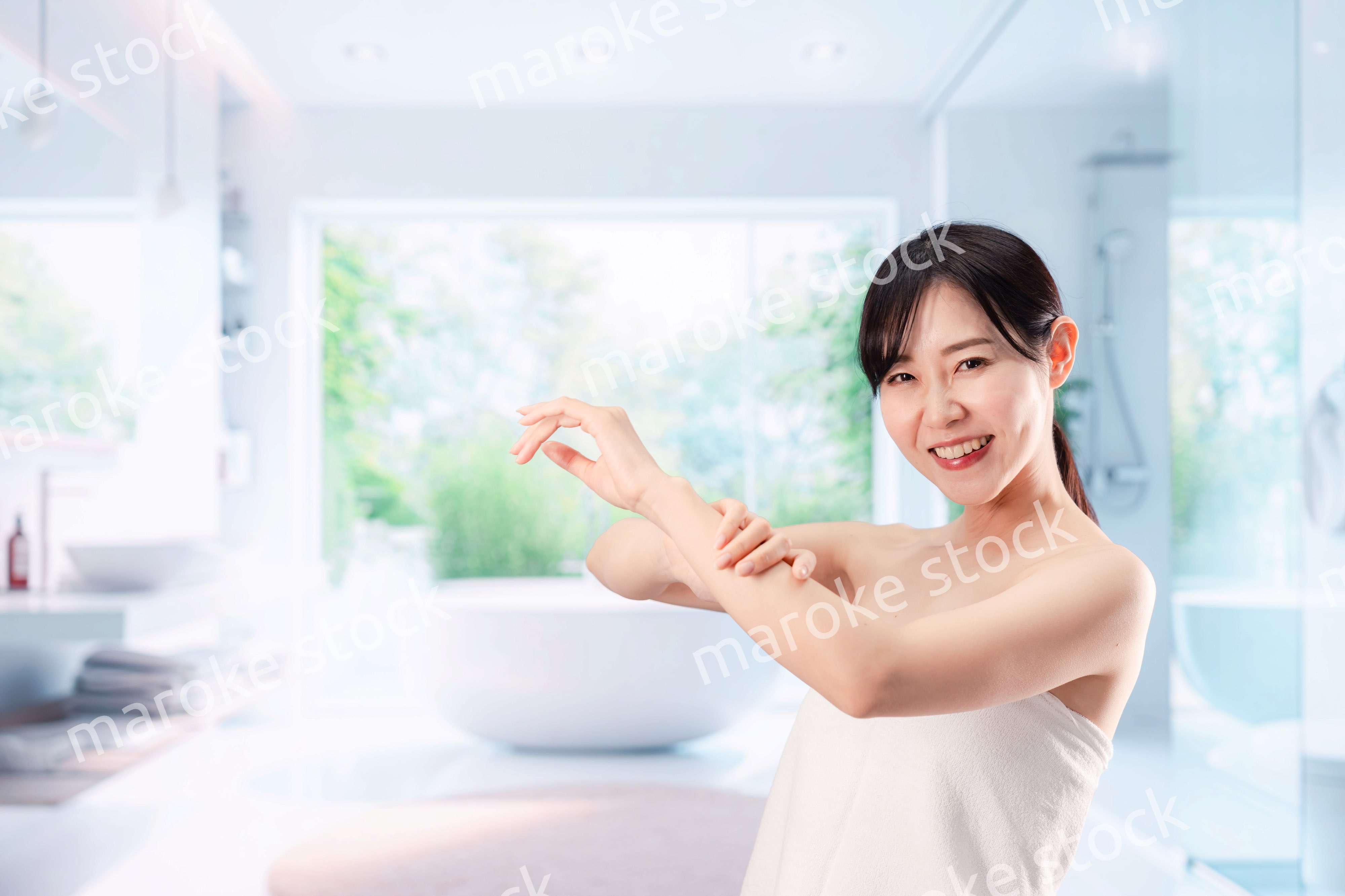 バスルームでボディケアをする若い女性