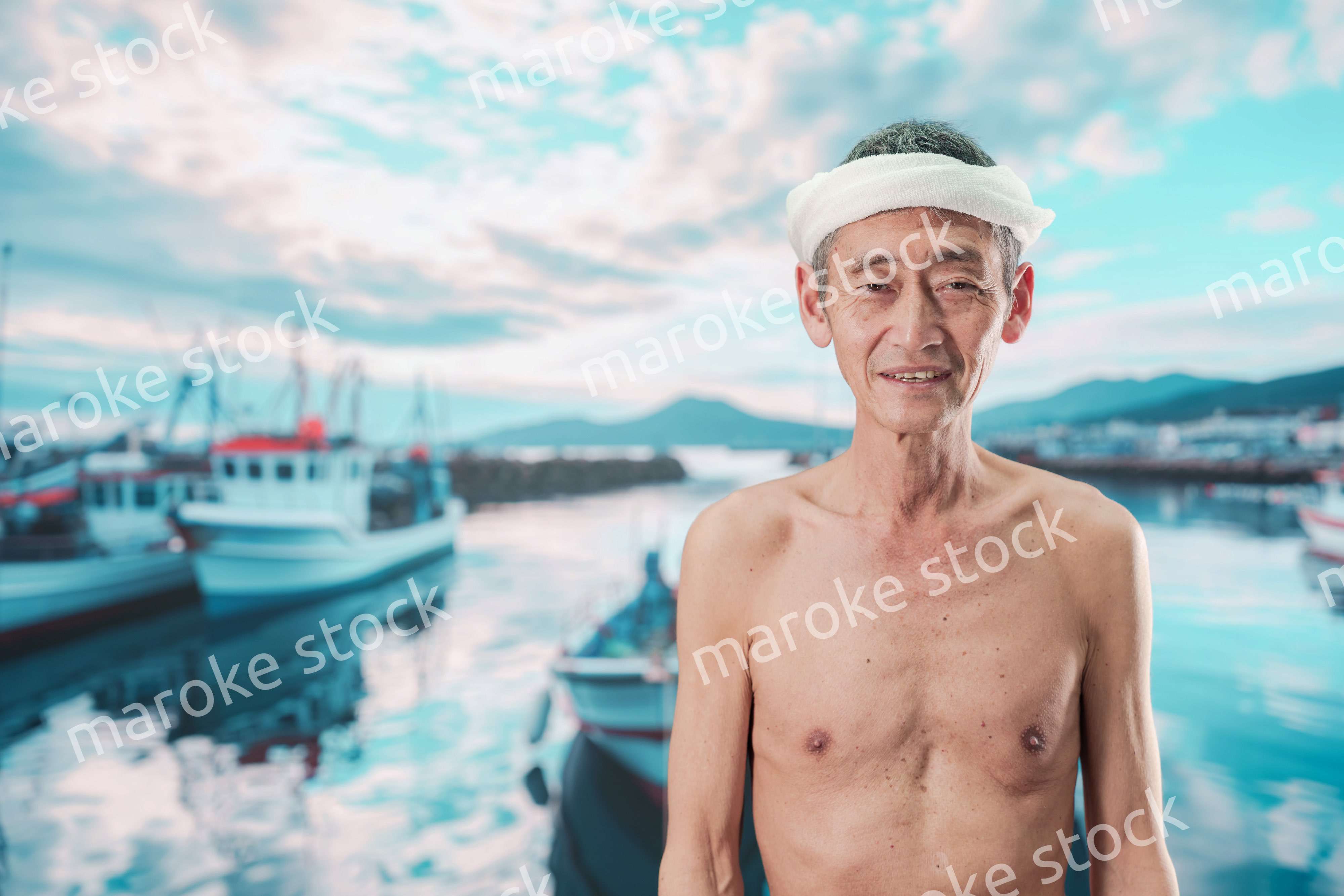 笑顔で腕を組む高齢の漁師