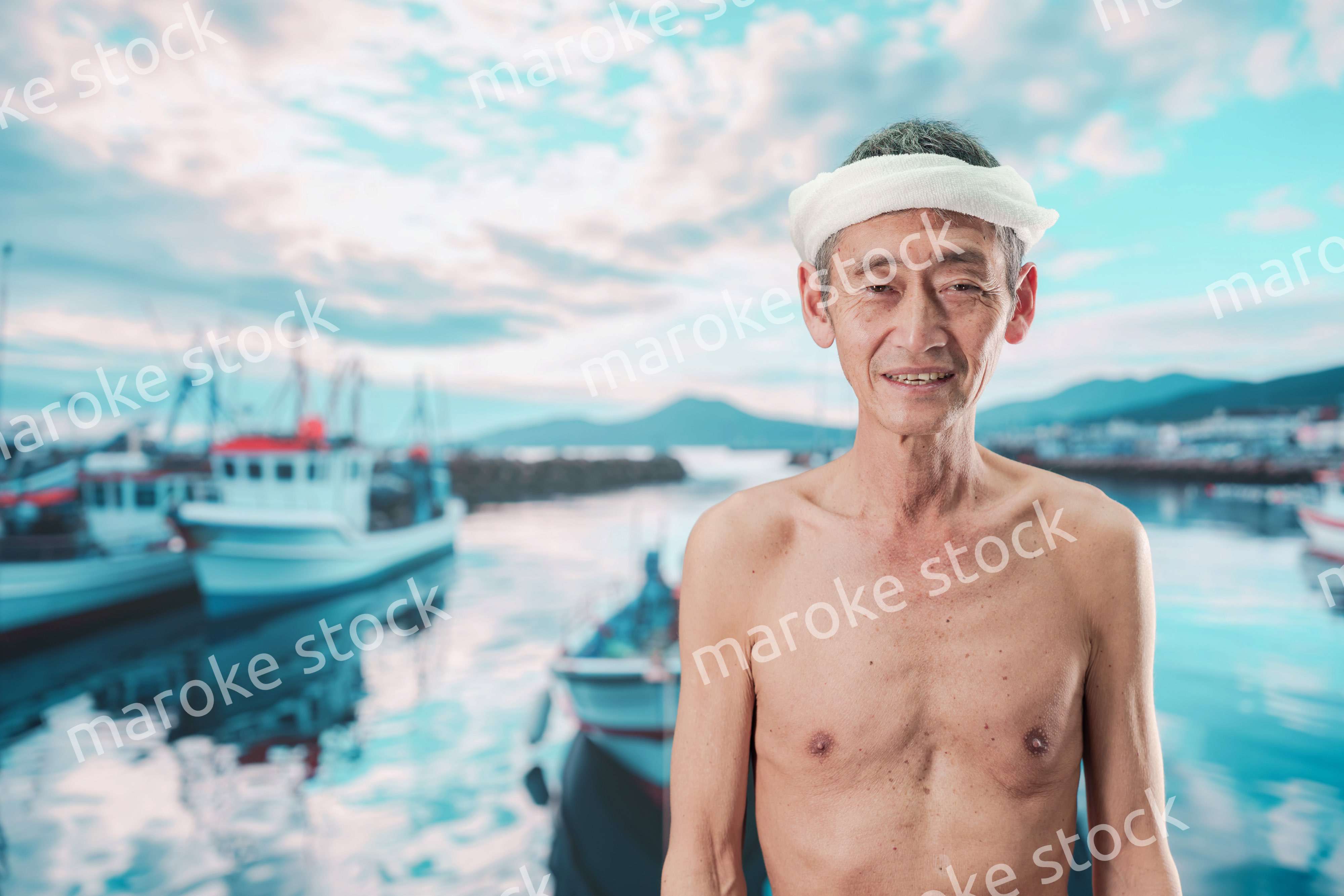 笑顔で腕を組む高齢の漁師