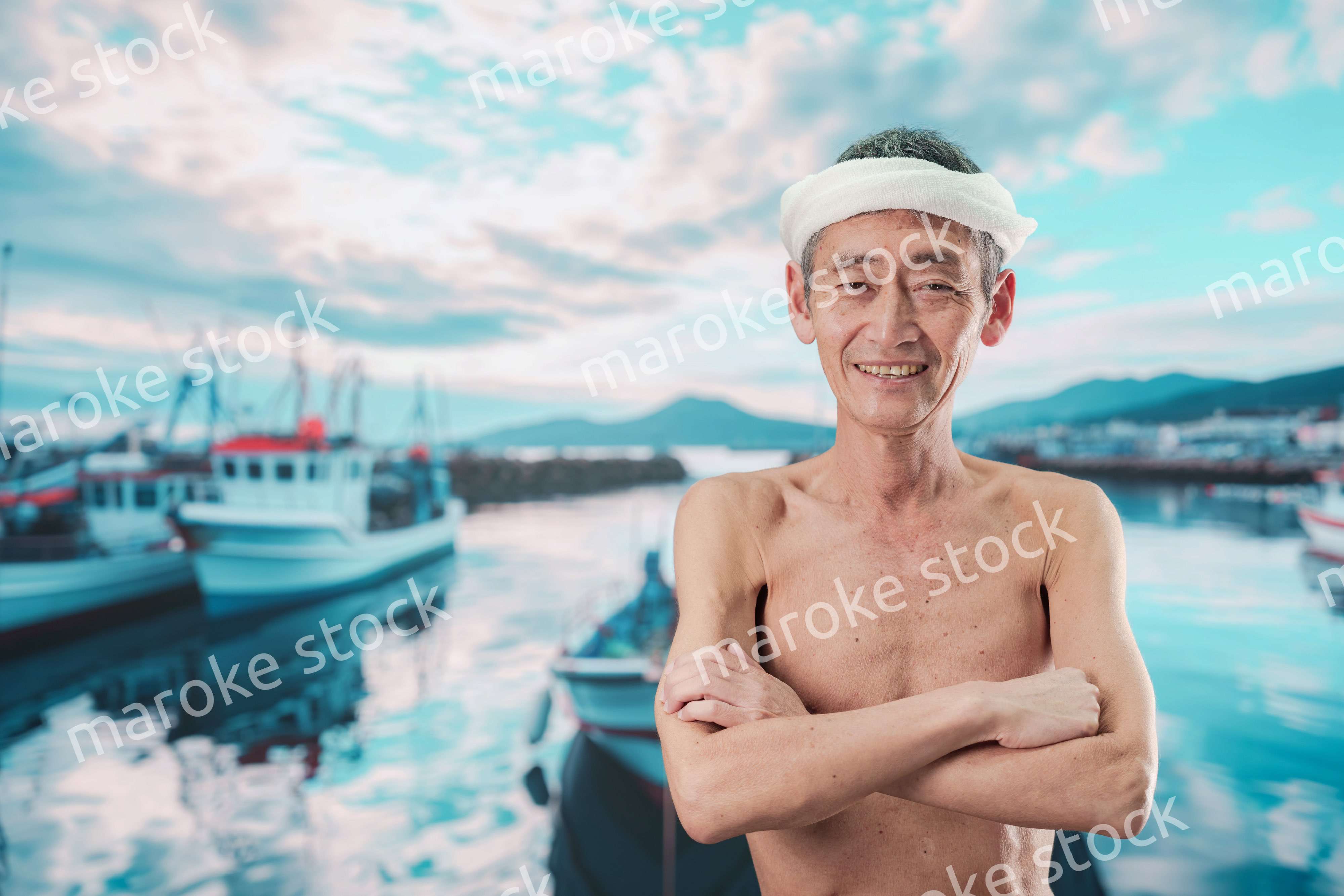 笑顔で腕を組む高齢の漁師