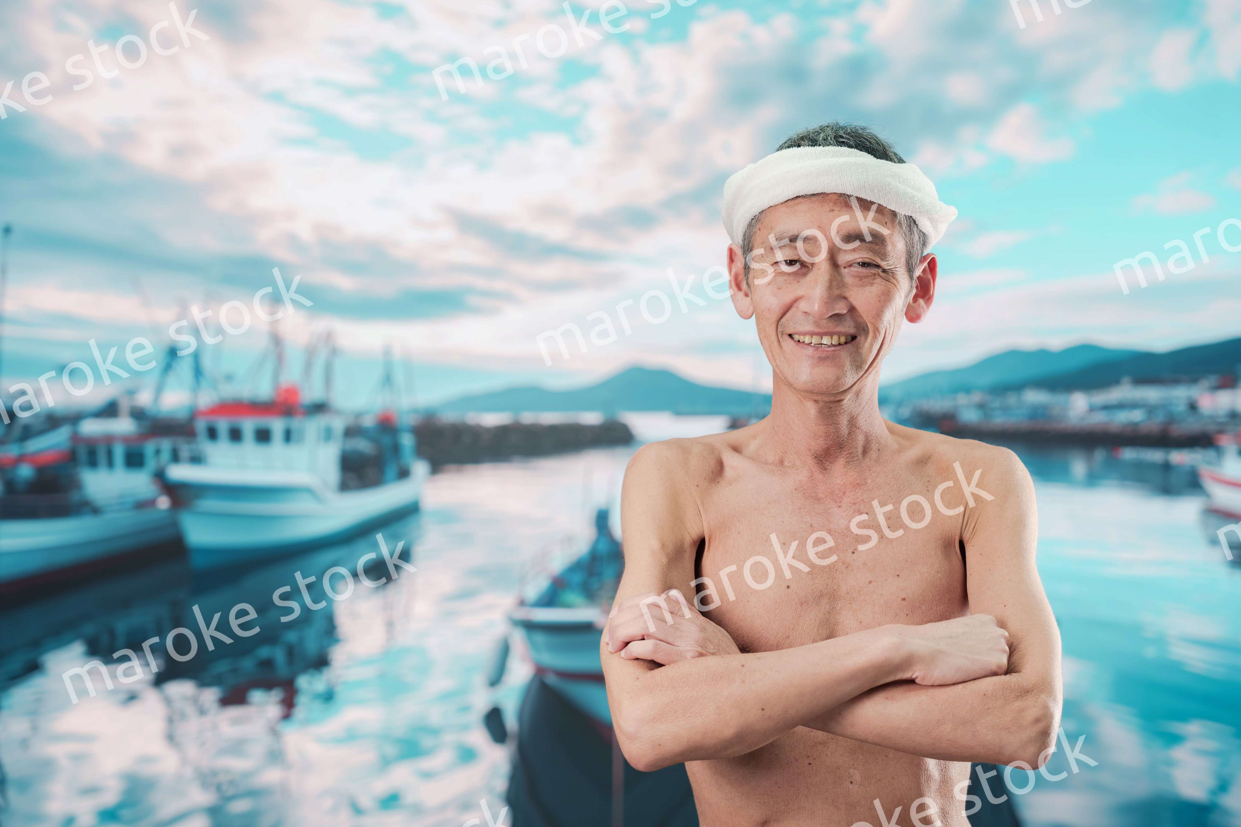 笑顔で腕を組む高齢の漁師