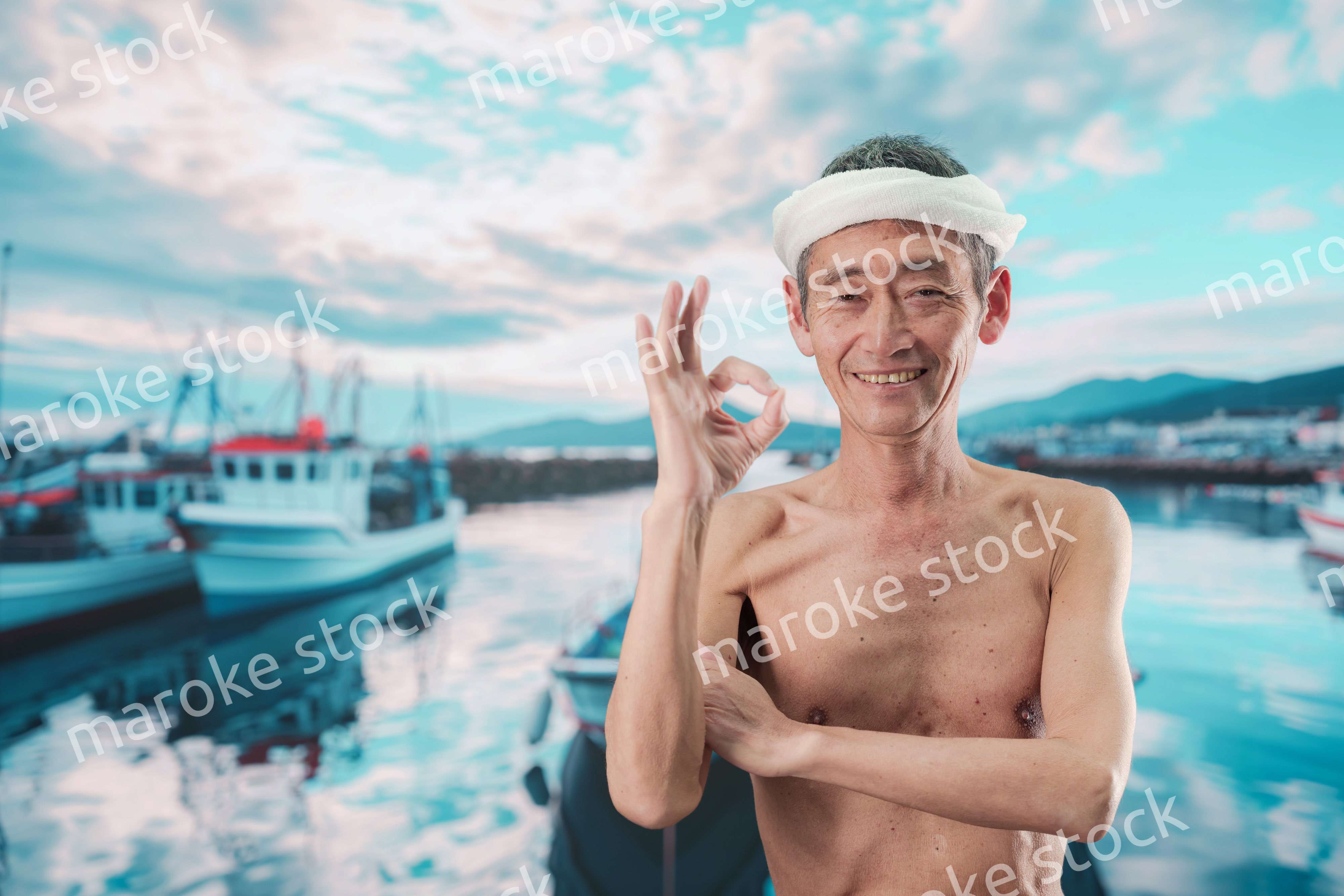 笑顔で腕を組む高齢の漁師