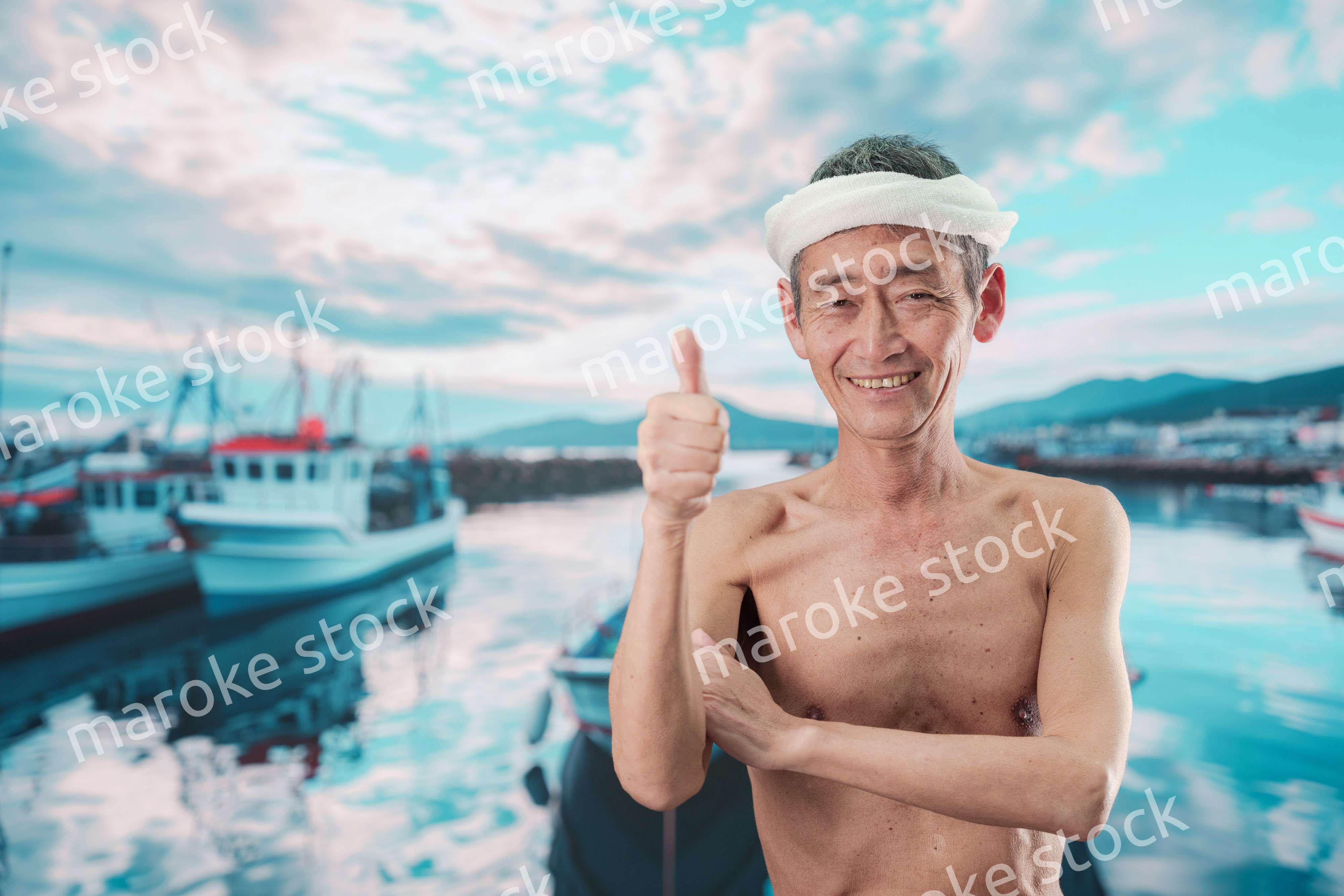 笑顔で腕を組む高齢の漁師