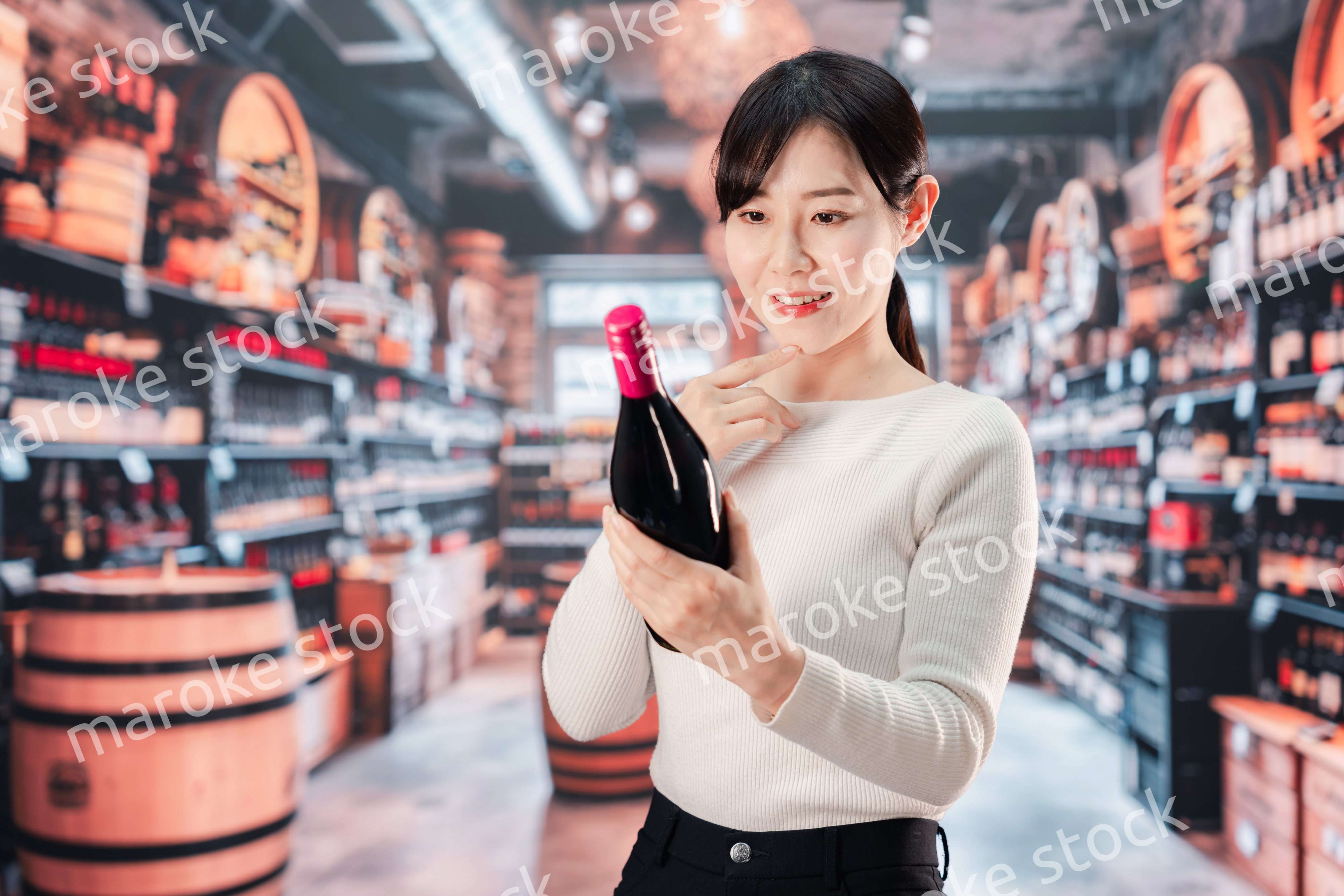 ワインショップでワインを選ぶ若い女性