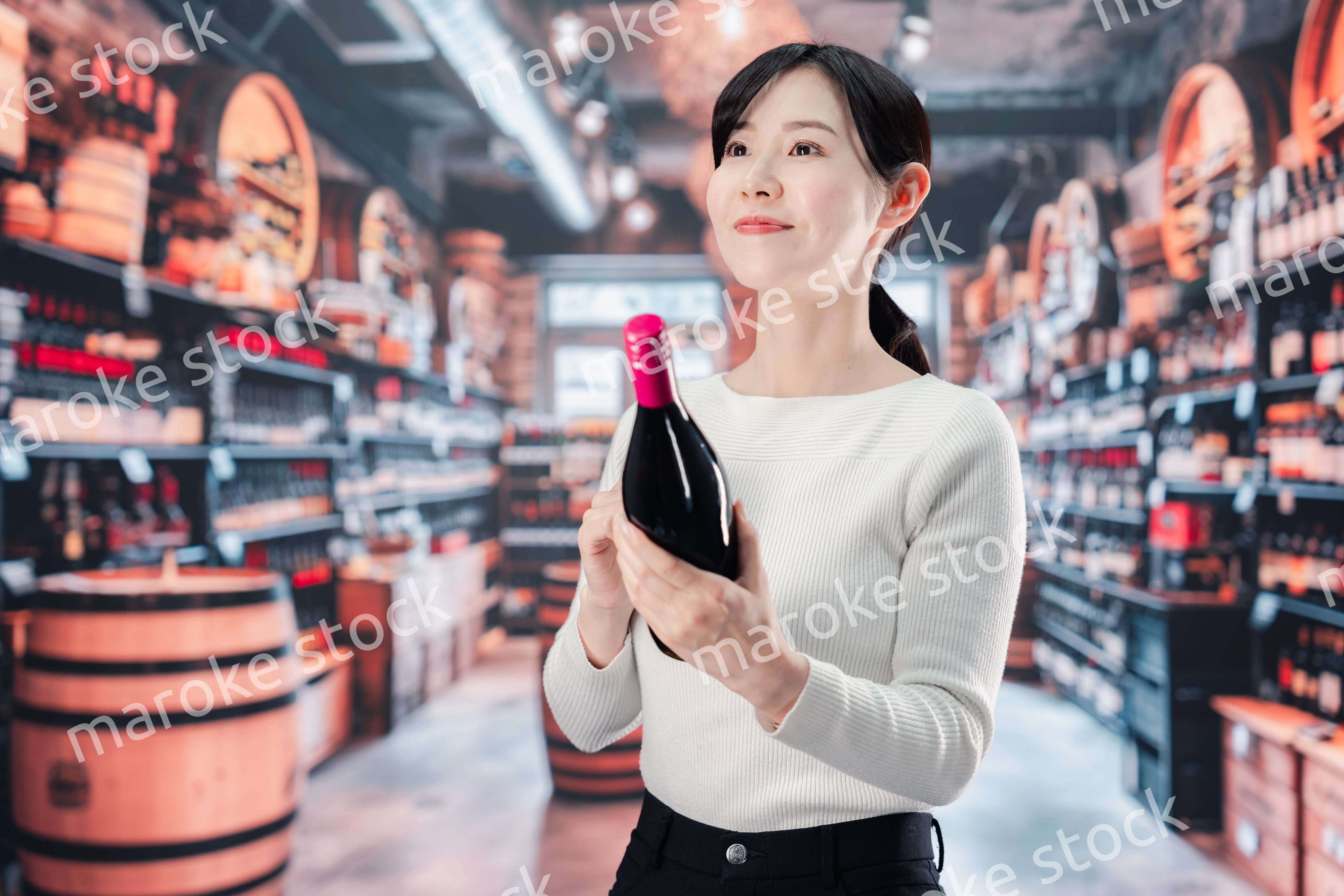 ワインショップでワインを選ぶ若い女性