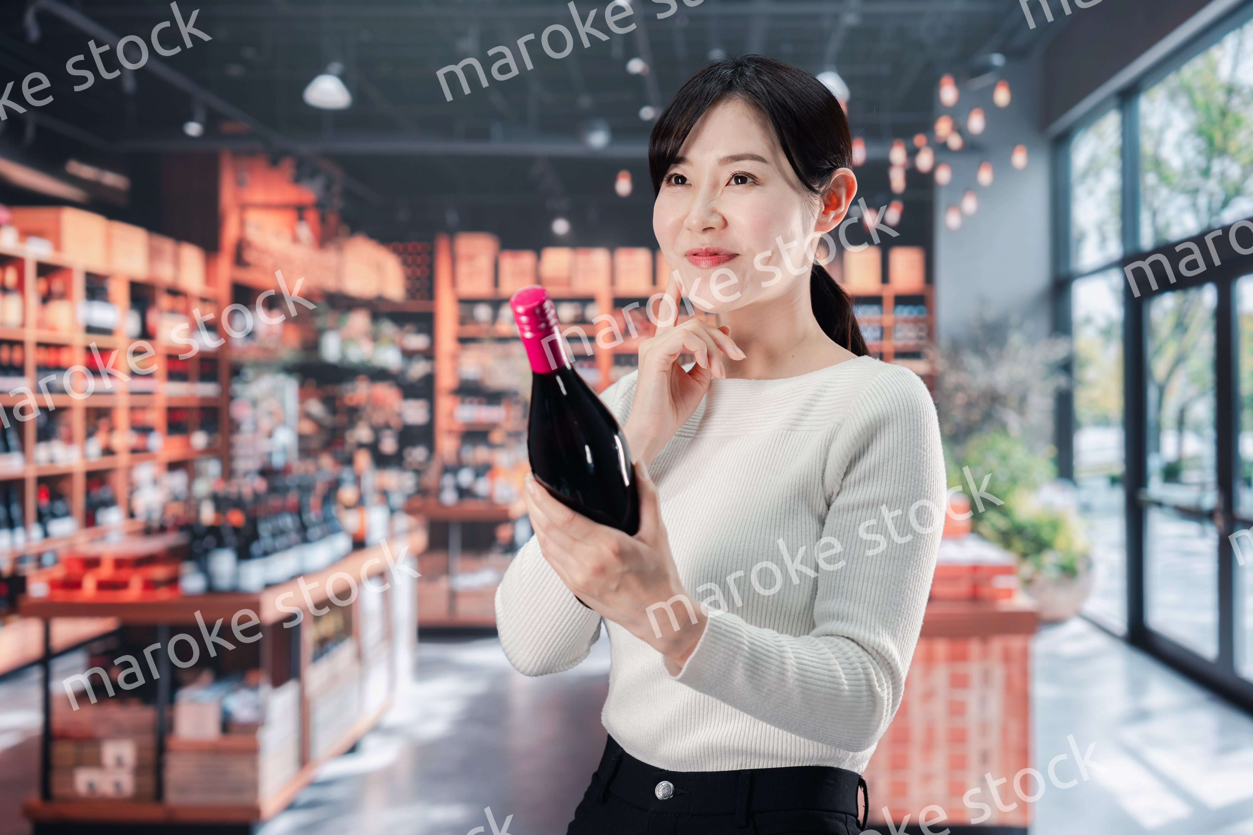 ワインショップでワインを選ぶ若い女性