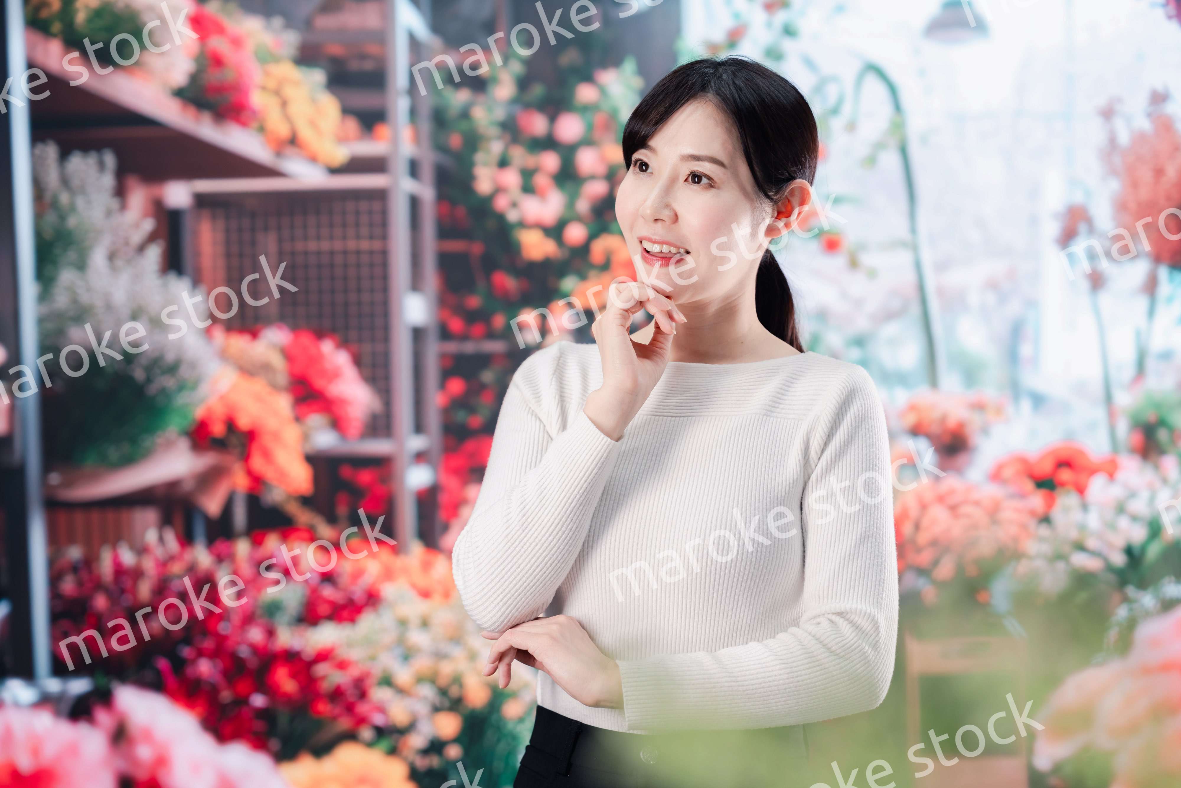 お花屋さんで花を選ぶ若い女性