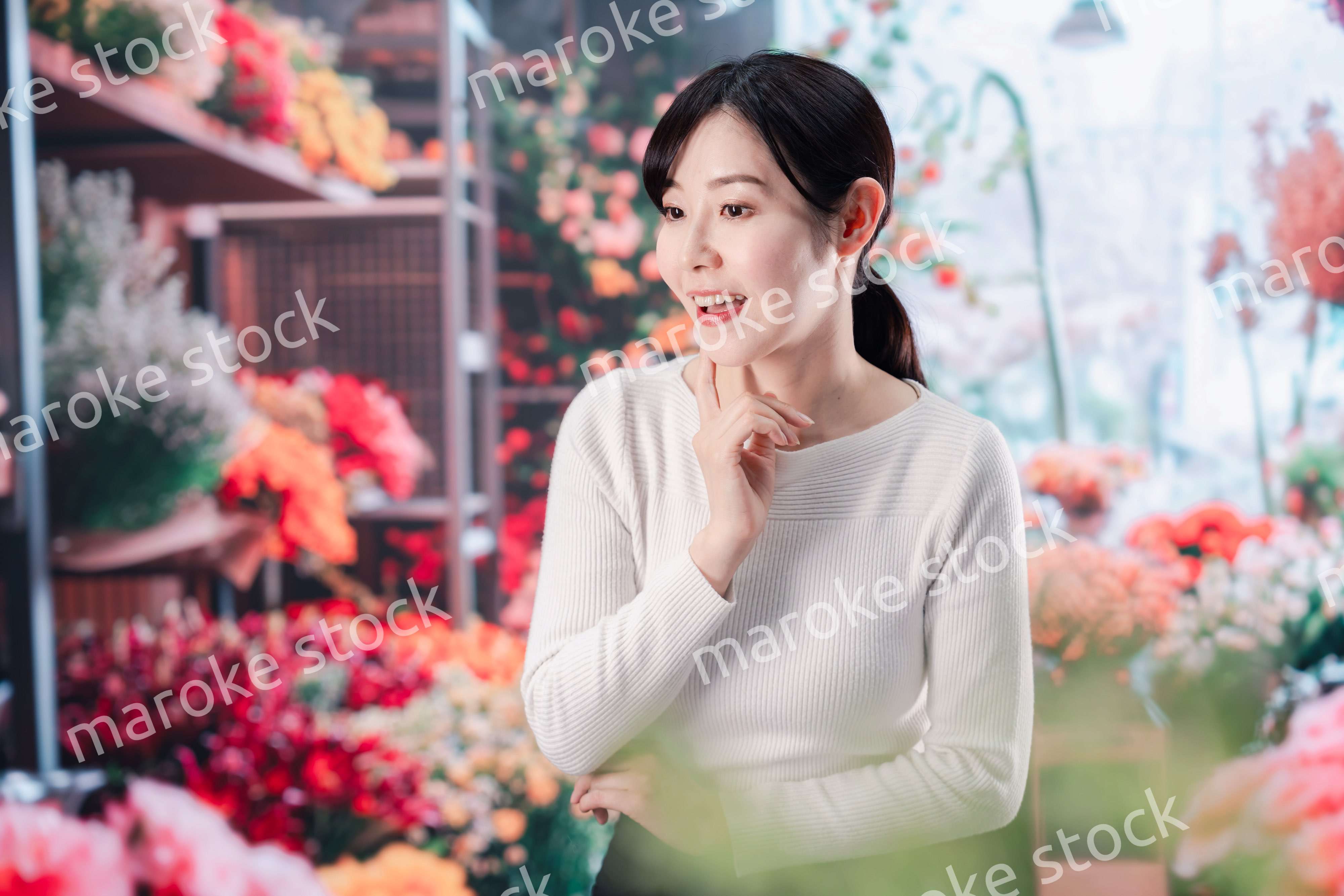 お花屋さんで花を選ぶ若い女性