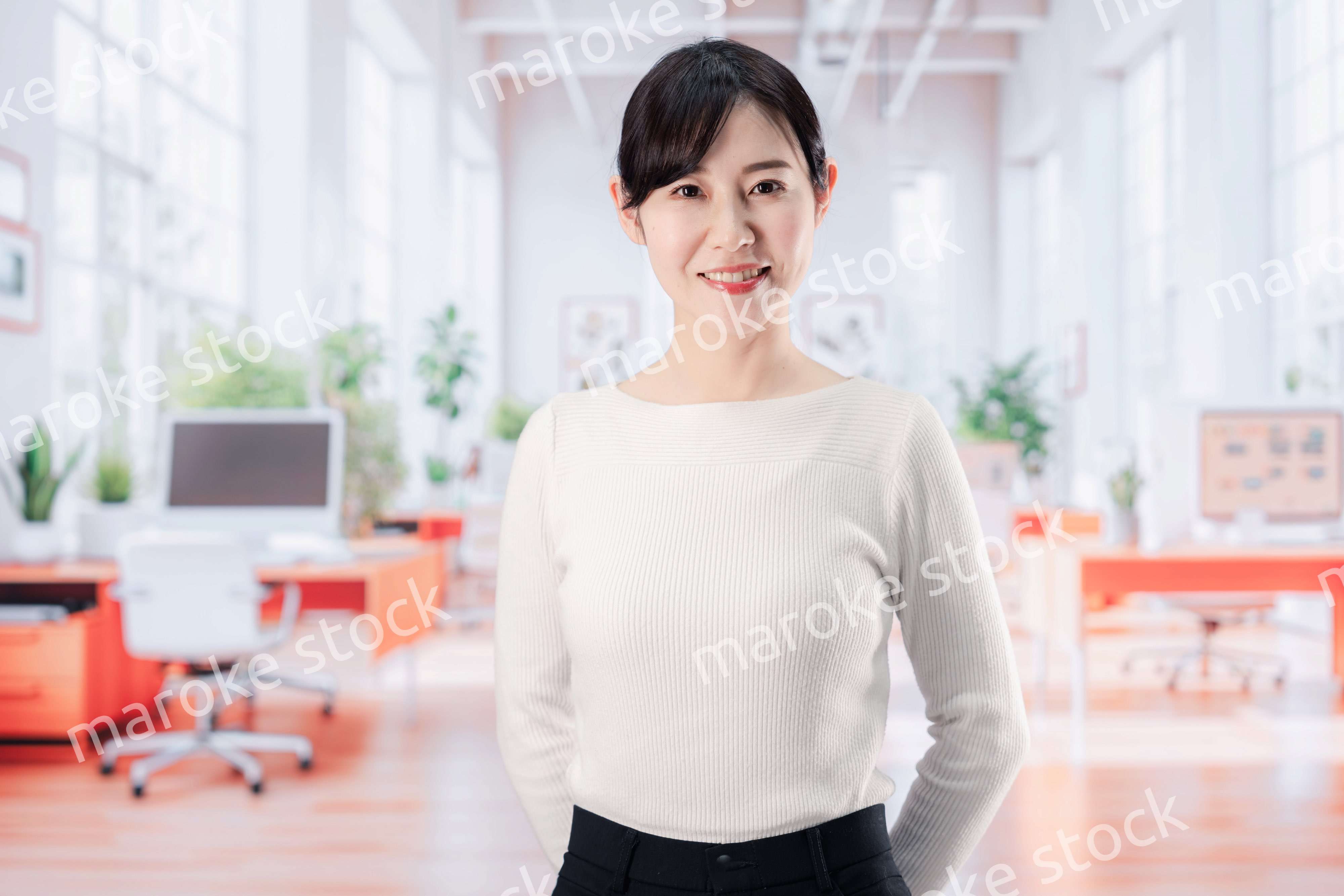 ビジネスカジュアルでオフィスに立つ若い女性