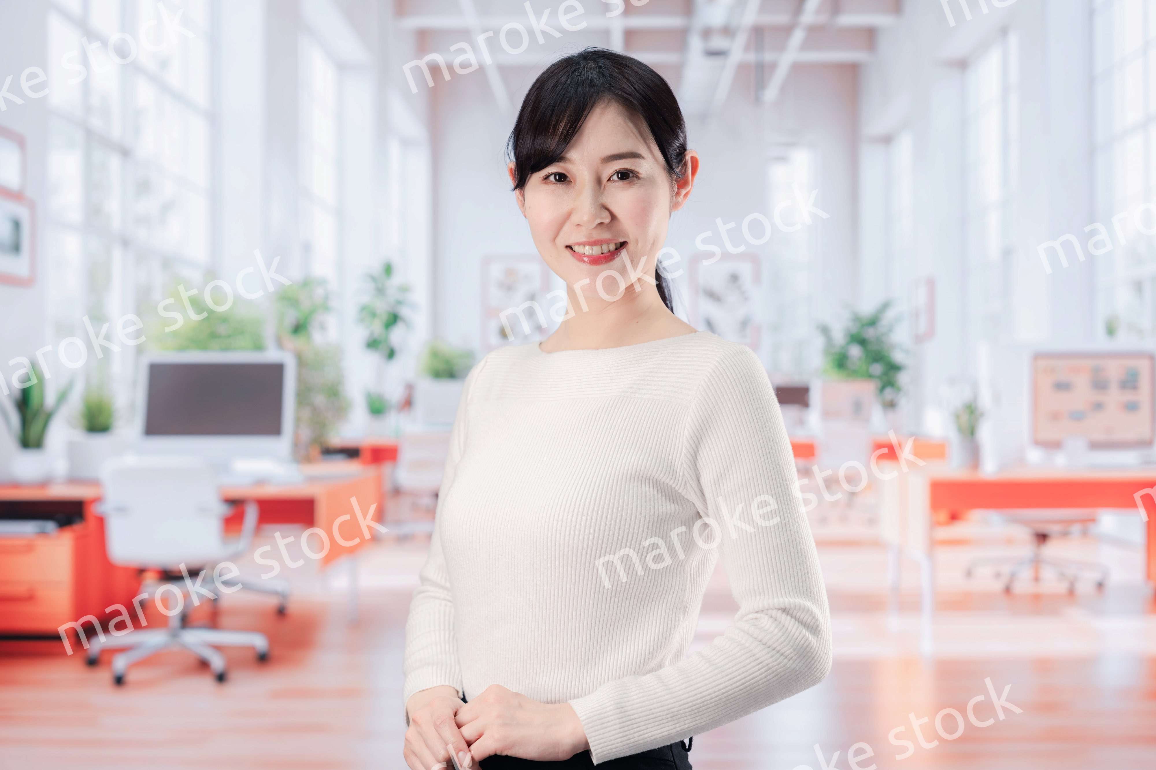 ビジネスカジュアルでオフィスに立つ若い女性