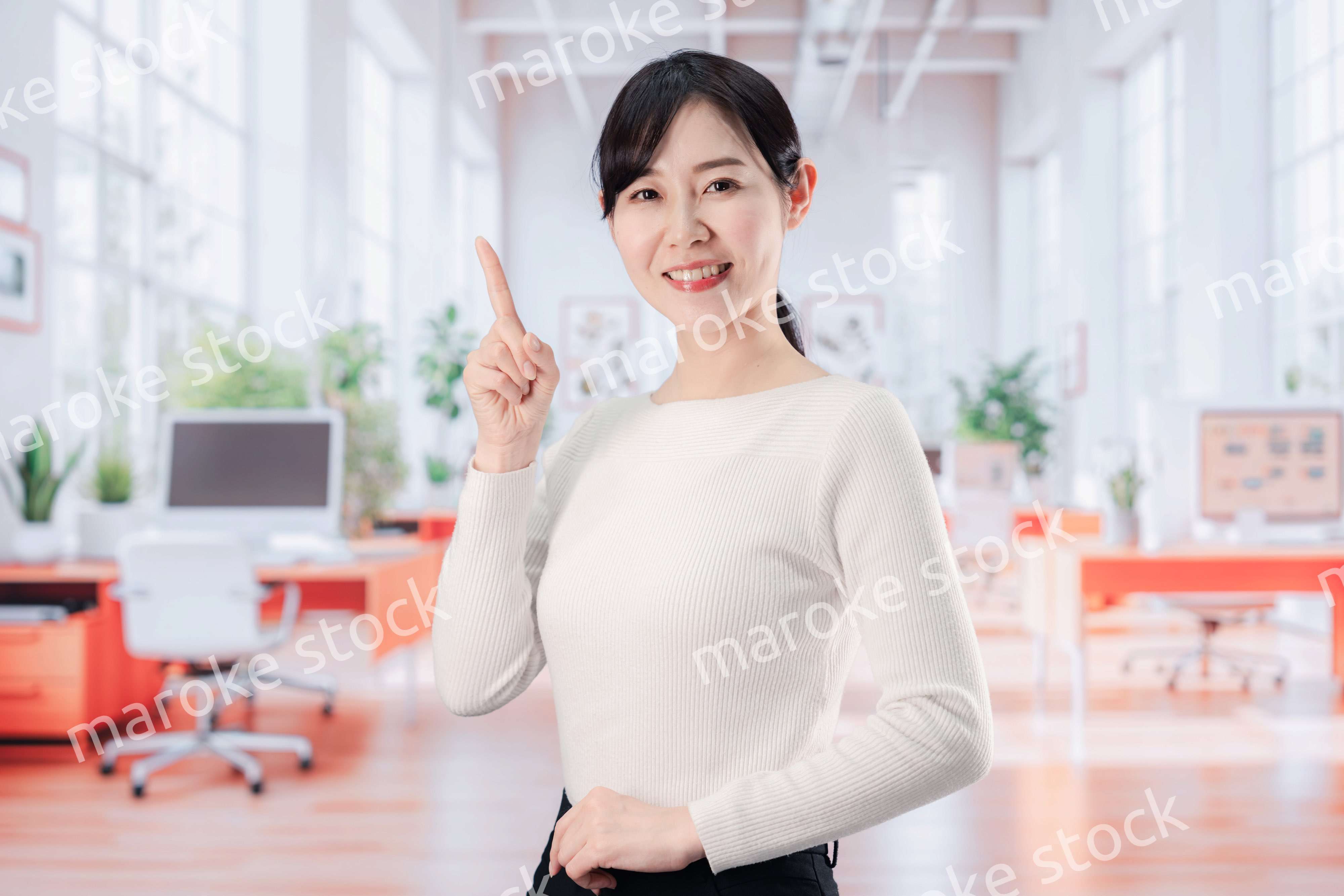 ビジネスカジュアルでオフィスに立つ若い女性