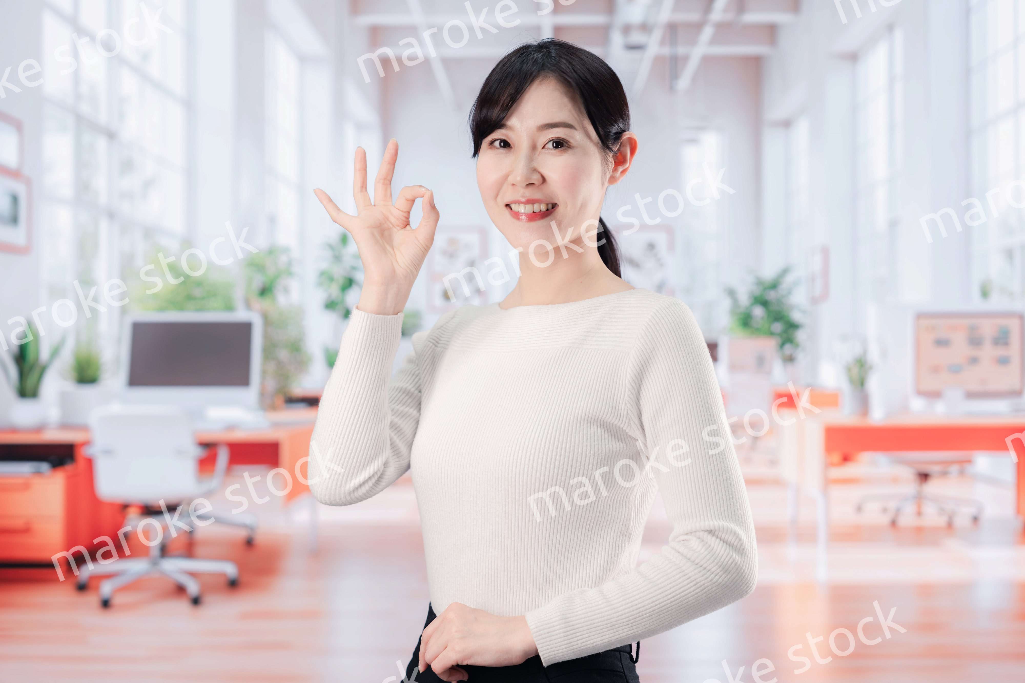 ビジネスカジュアルでオフィスに立つ若い女性