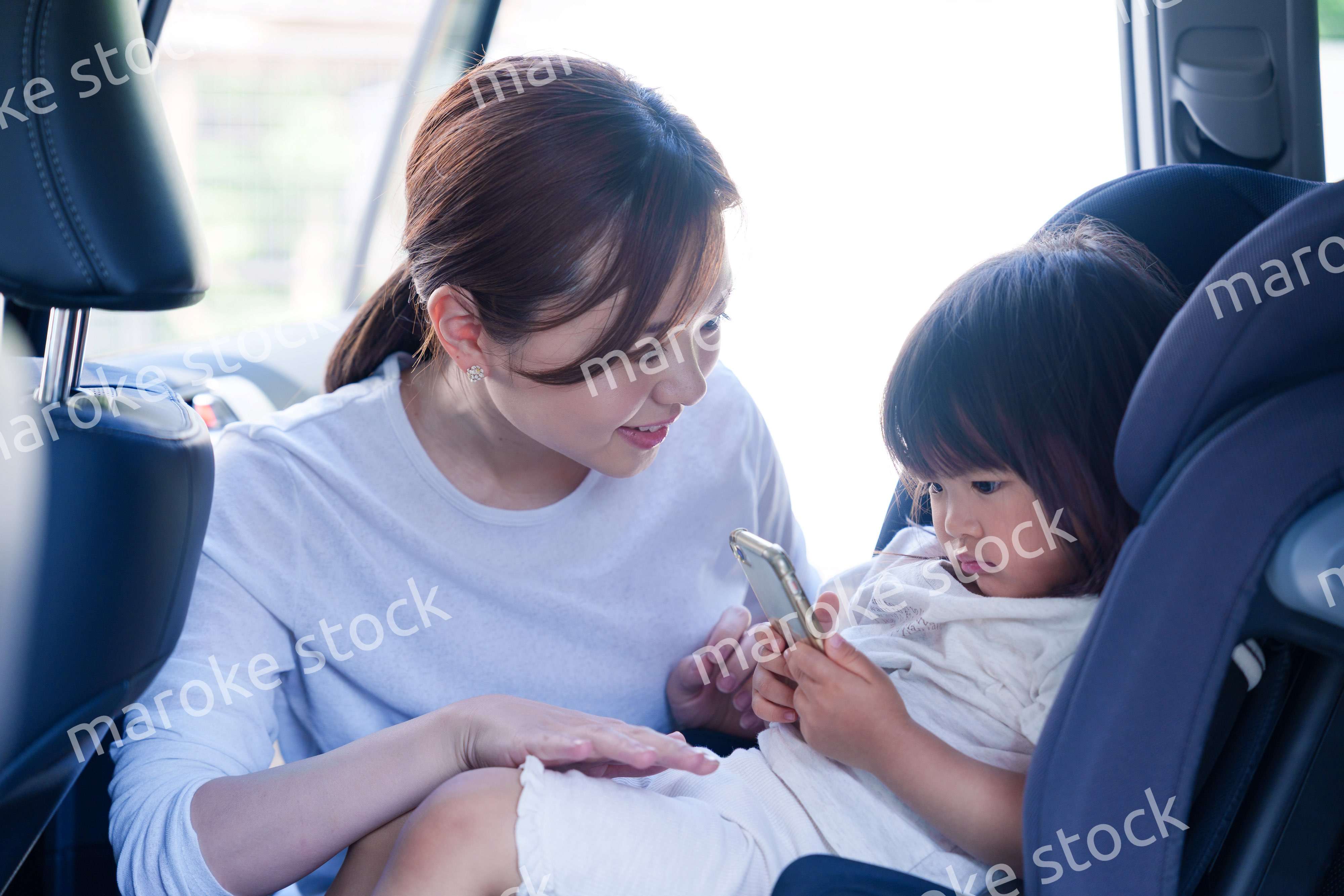 車でお出かけをする小さな子供とお母さん