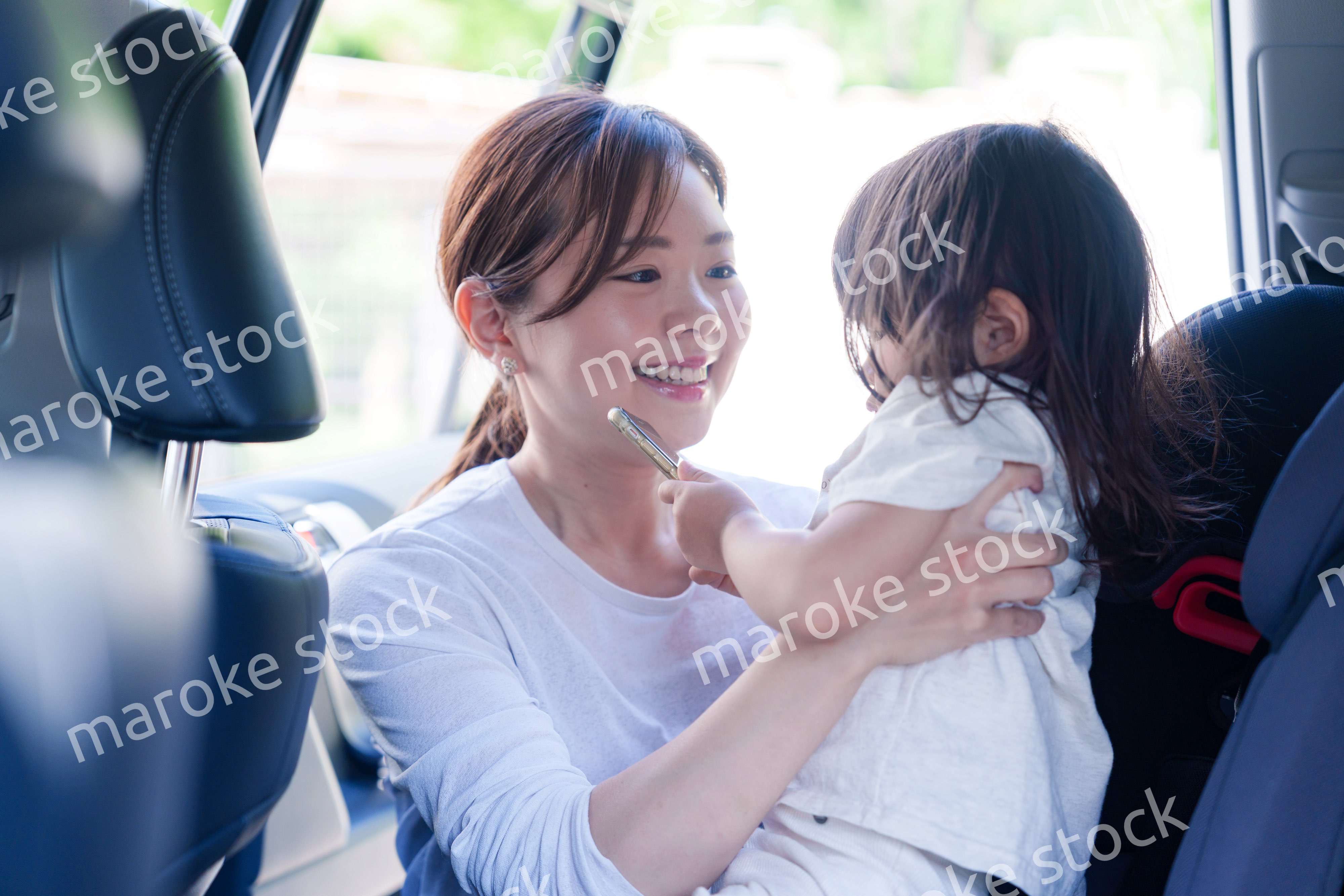 車でお出かけをする小さな子供とお母さん