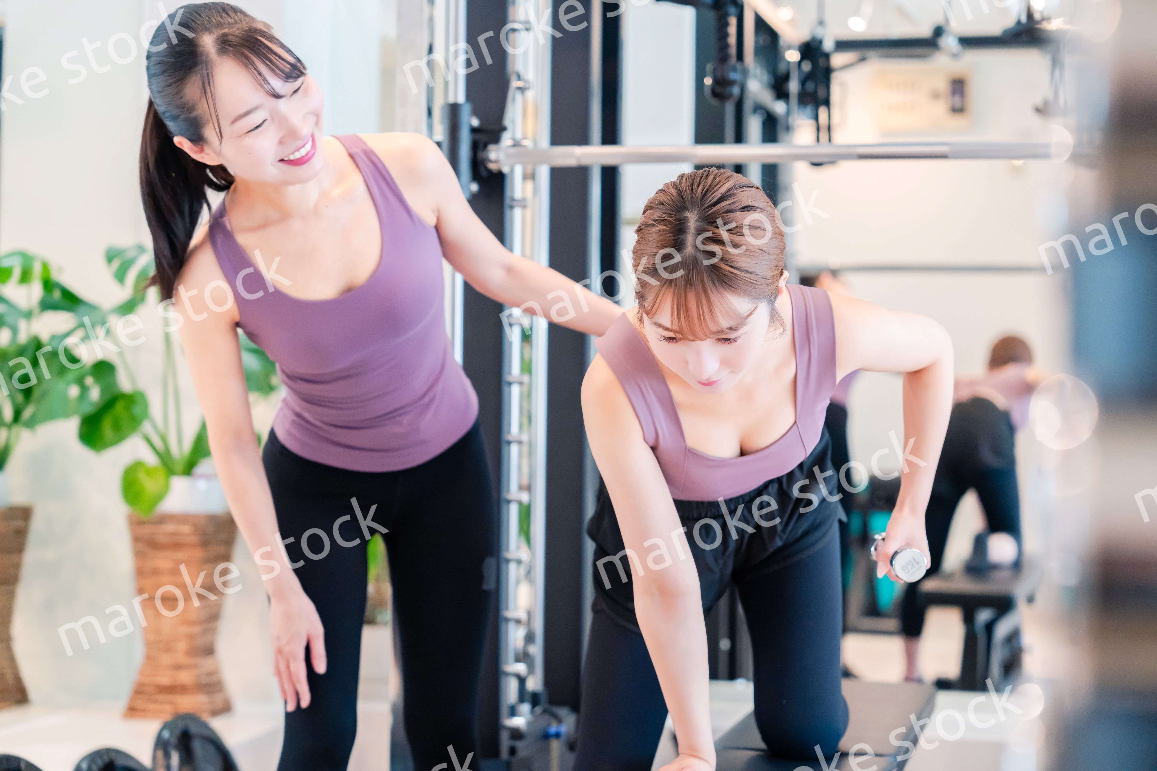 ジムで女性コーチのパーソナルトレーニングを受ける女性