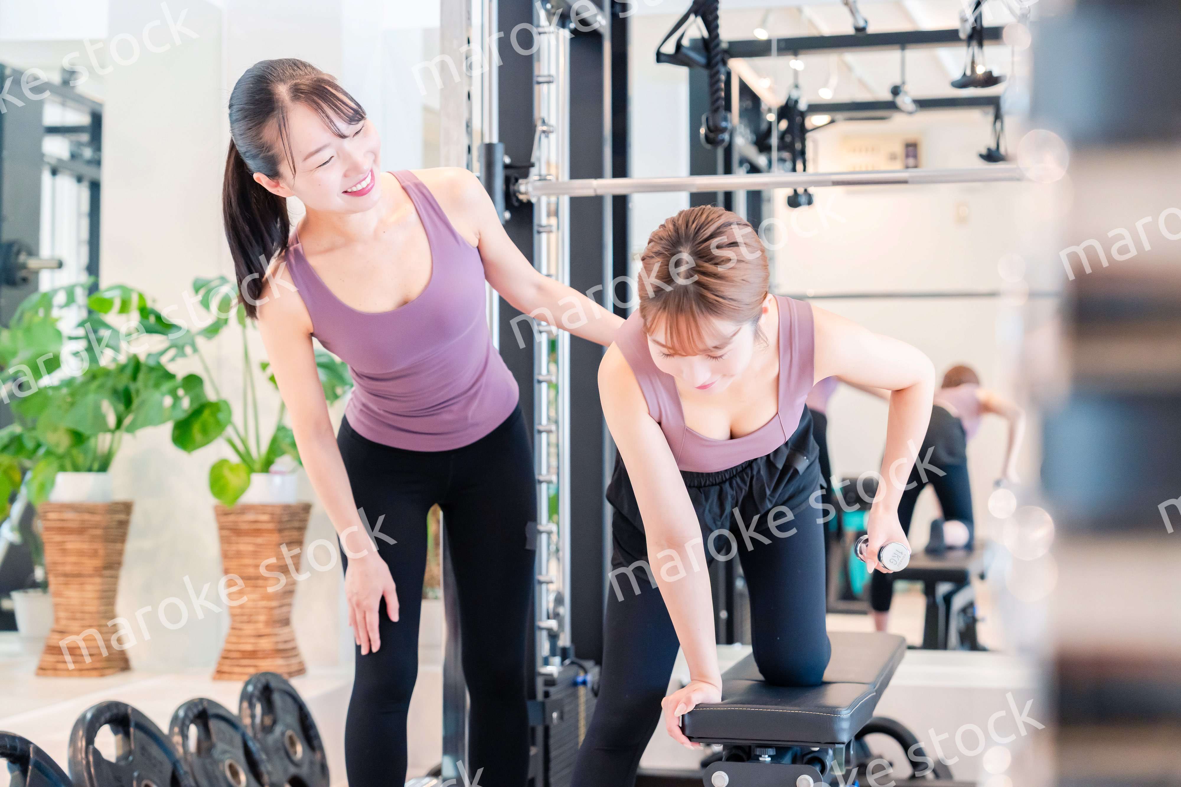 ジムで女性コーチのパーソナルトレーニングを受ける女性