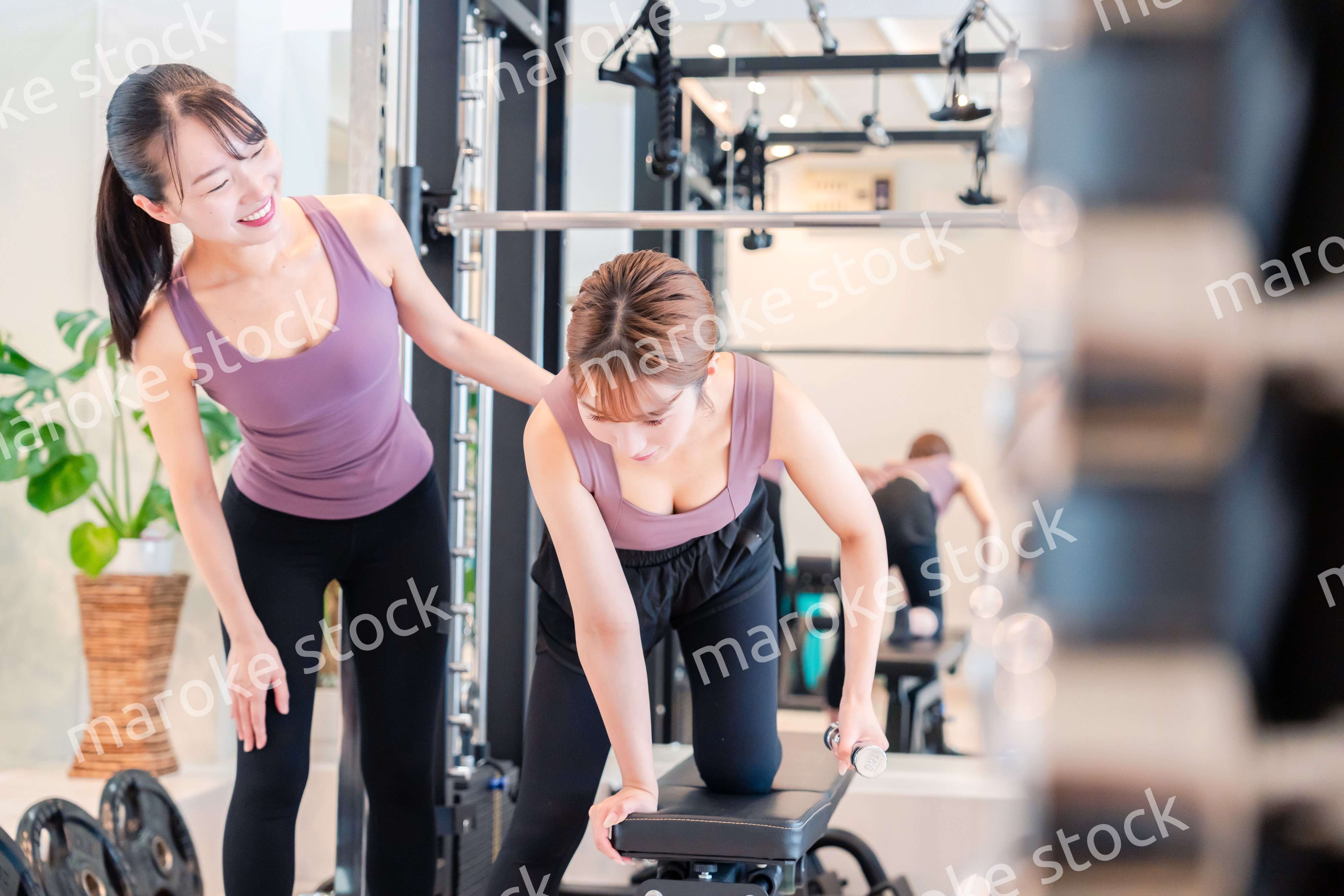 ジムで女性コーチのパーソナルトレーニングを受ける女性