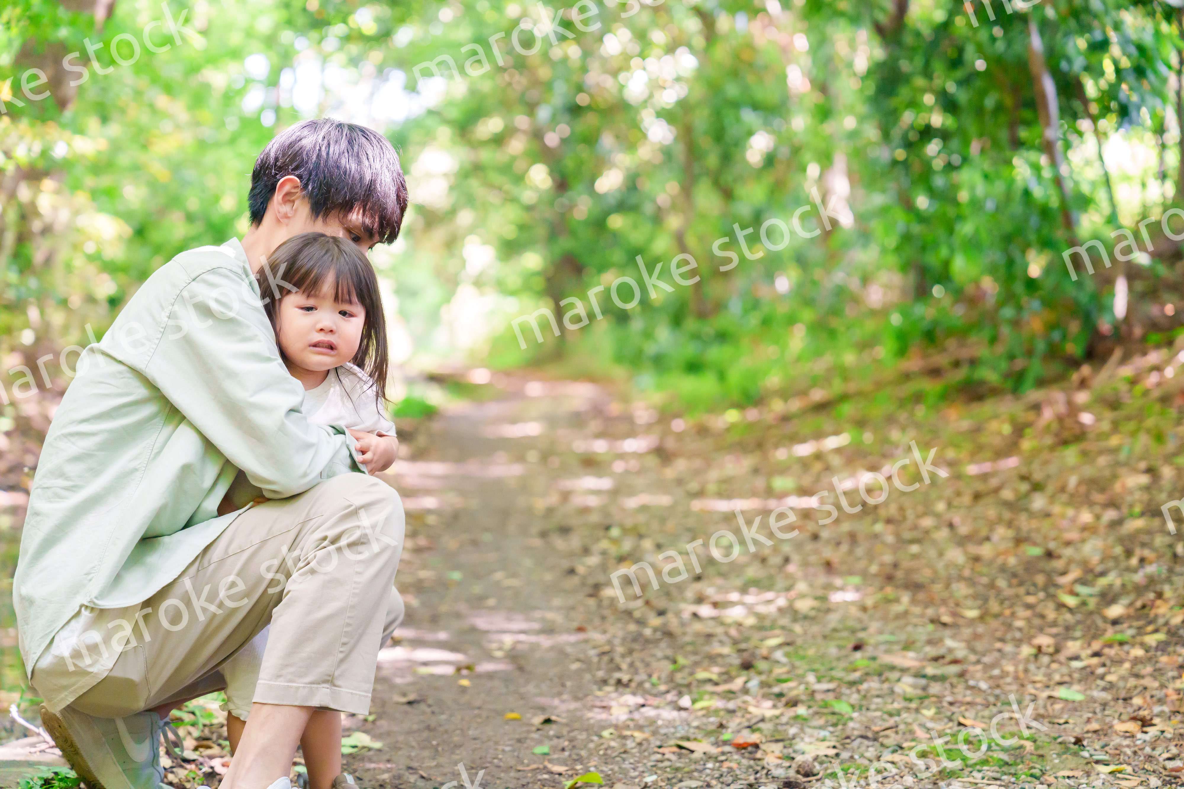 涙を流す小さな女の子を抱っこするパパ