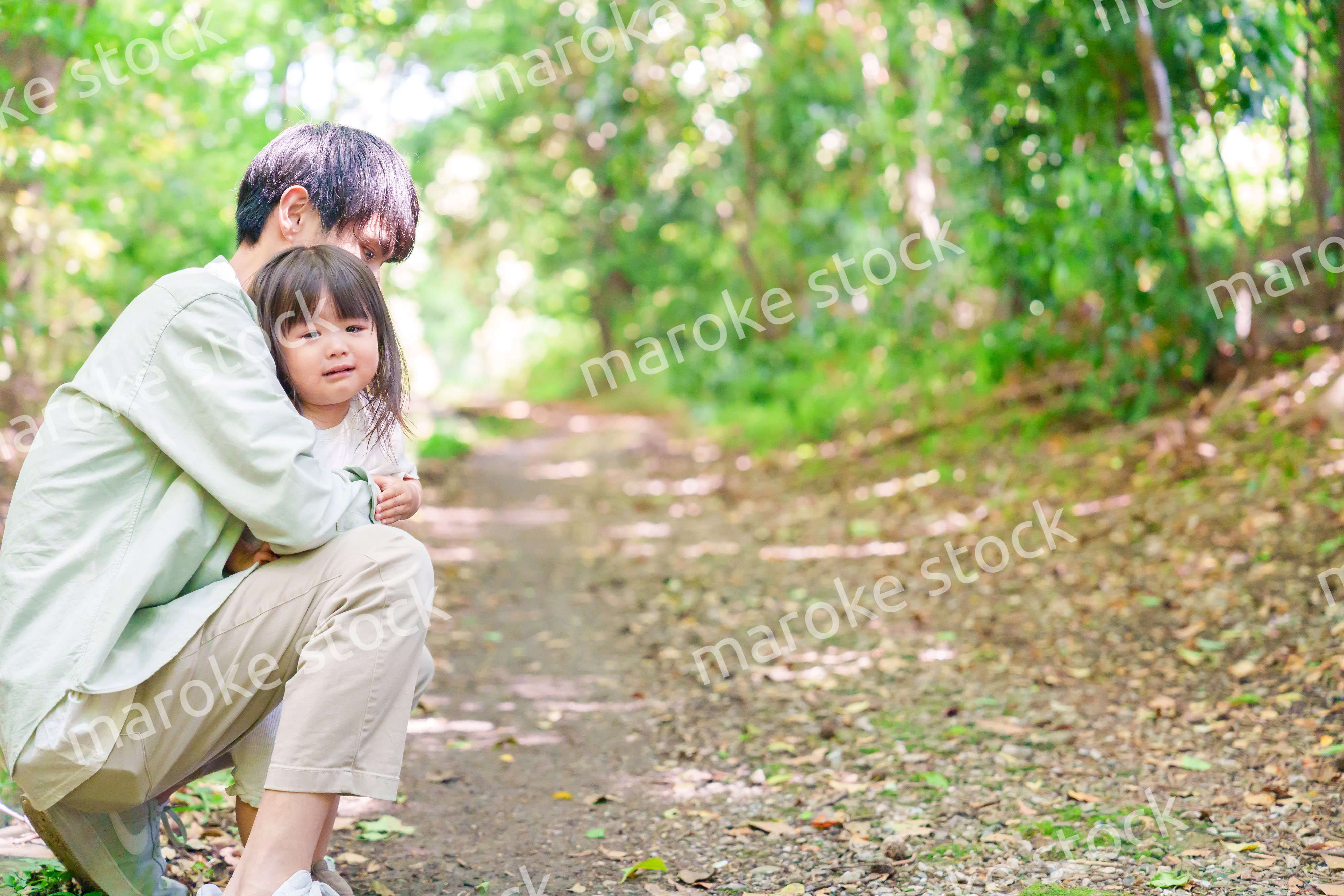 涙を流す小さな女の子を抱っこするパパ