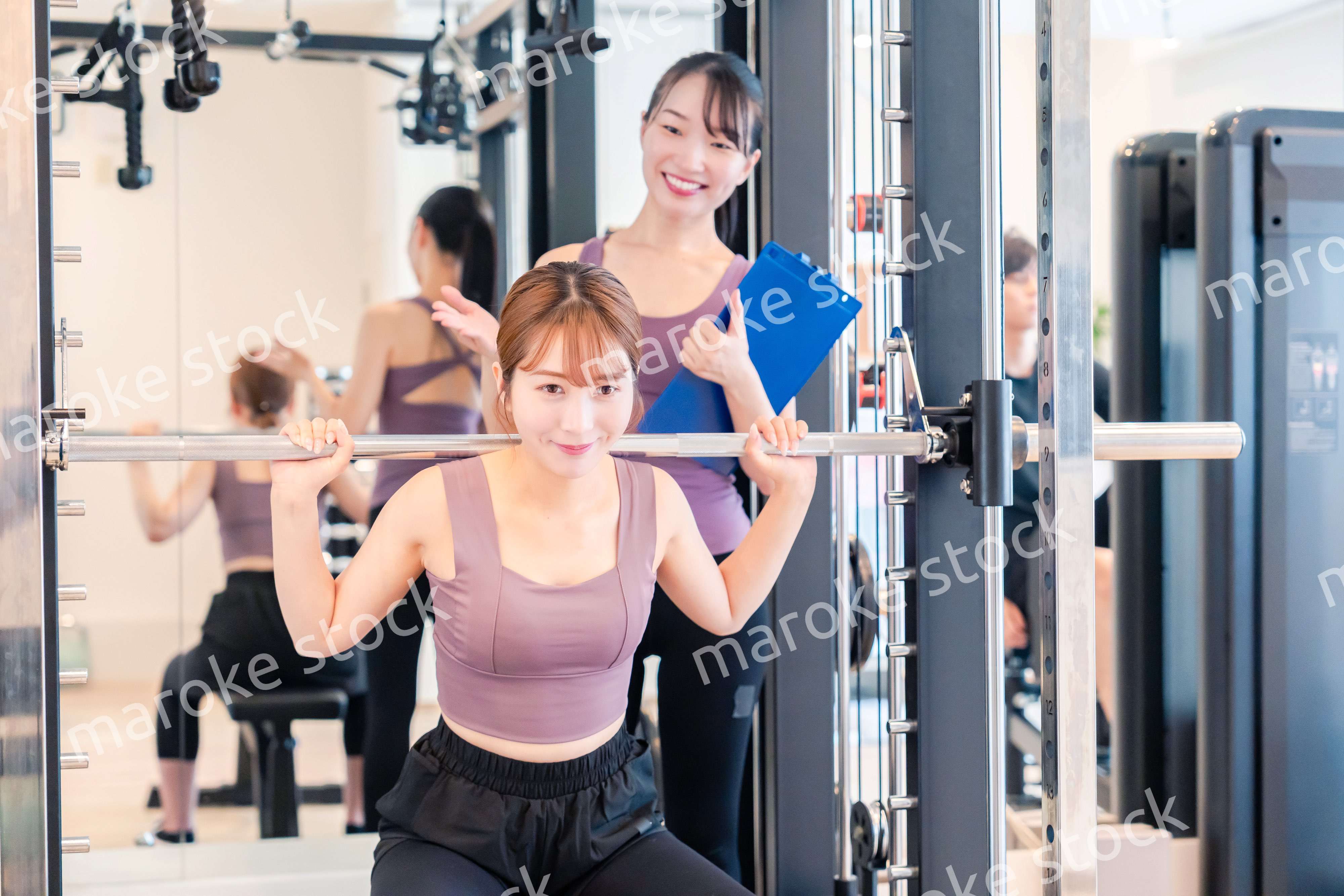 ジムで女性コーチのパーソナルトレーニングを受ける女性