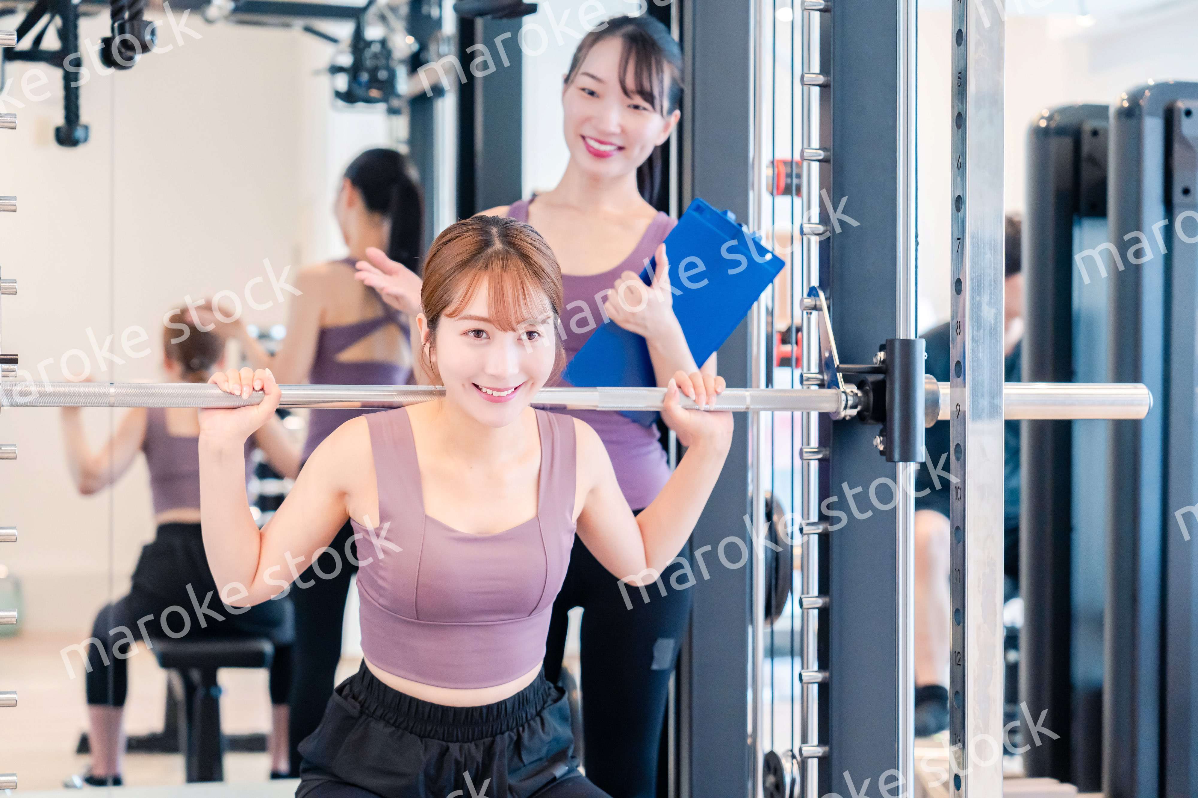 ジムで女性コーチのパーソナルトレーニングを受ける女性