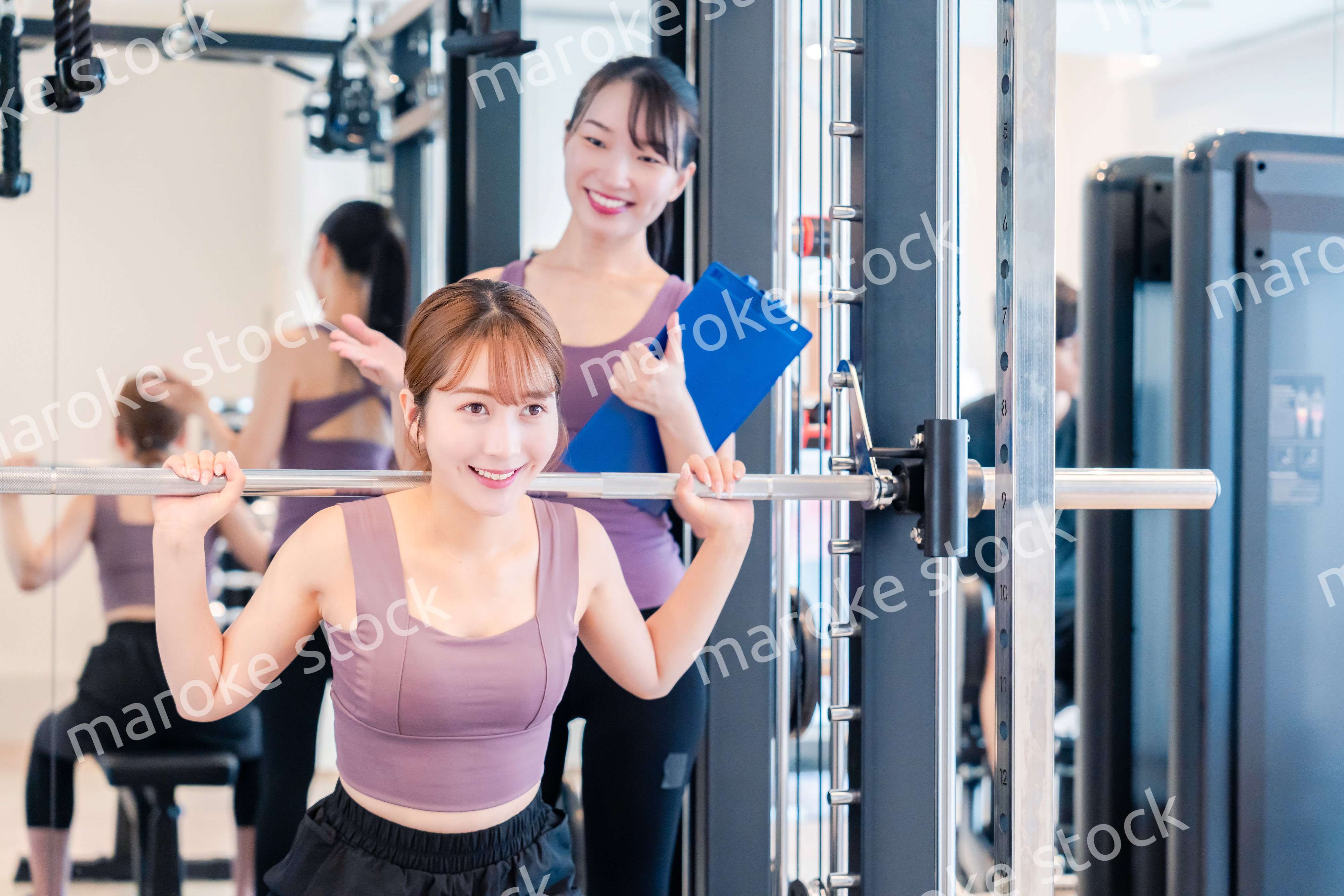 ジムで女性コーチのパーソナルトレーニングを受ける女性