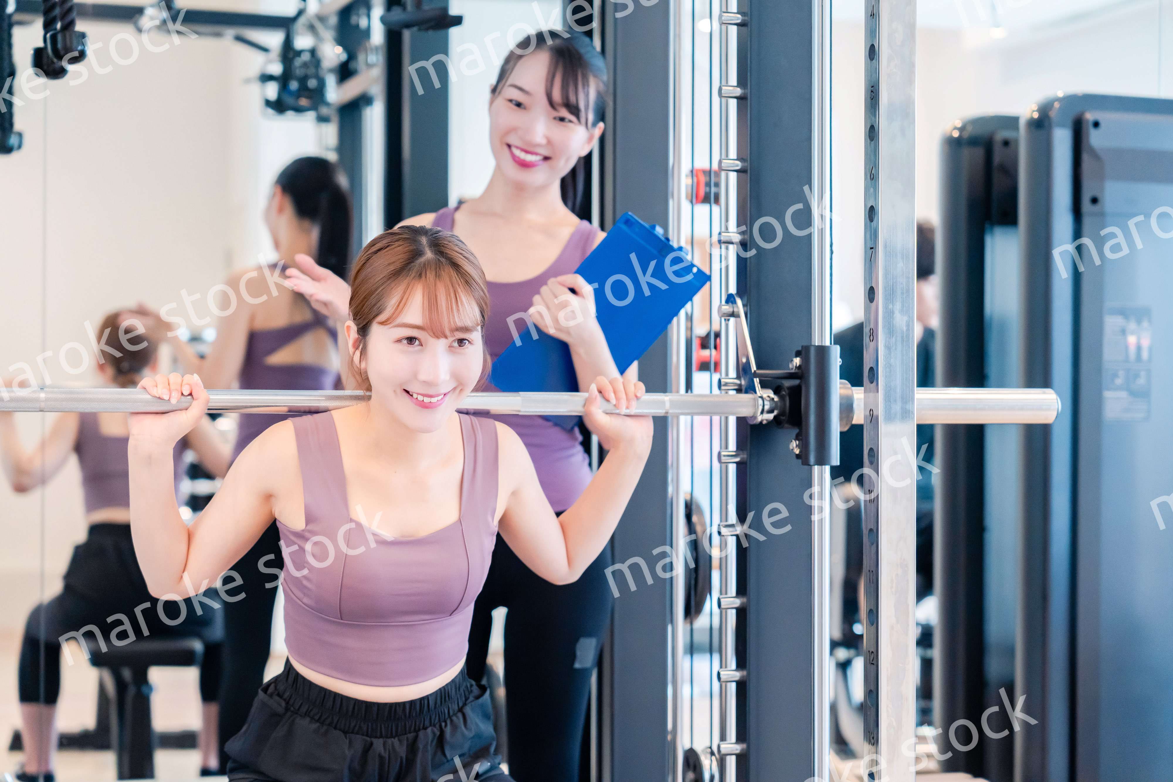 ジムで女性コーチのパーソナルトレーニングを受ける女性