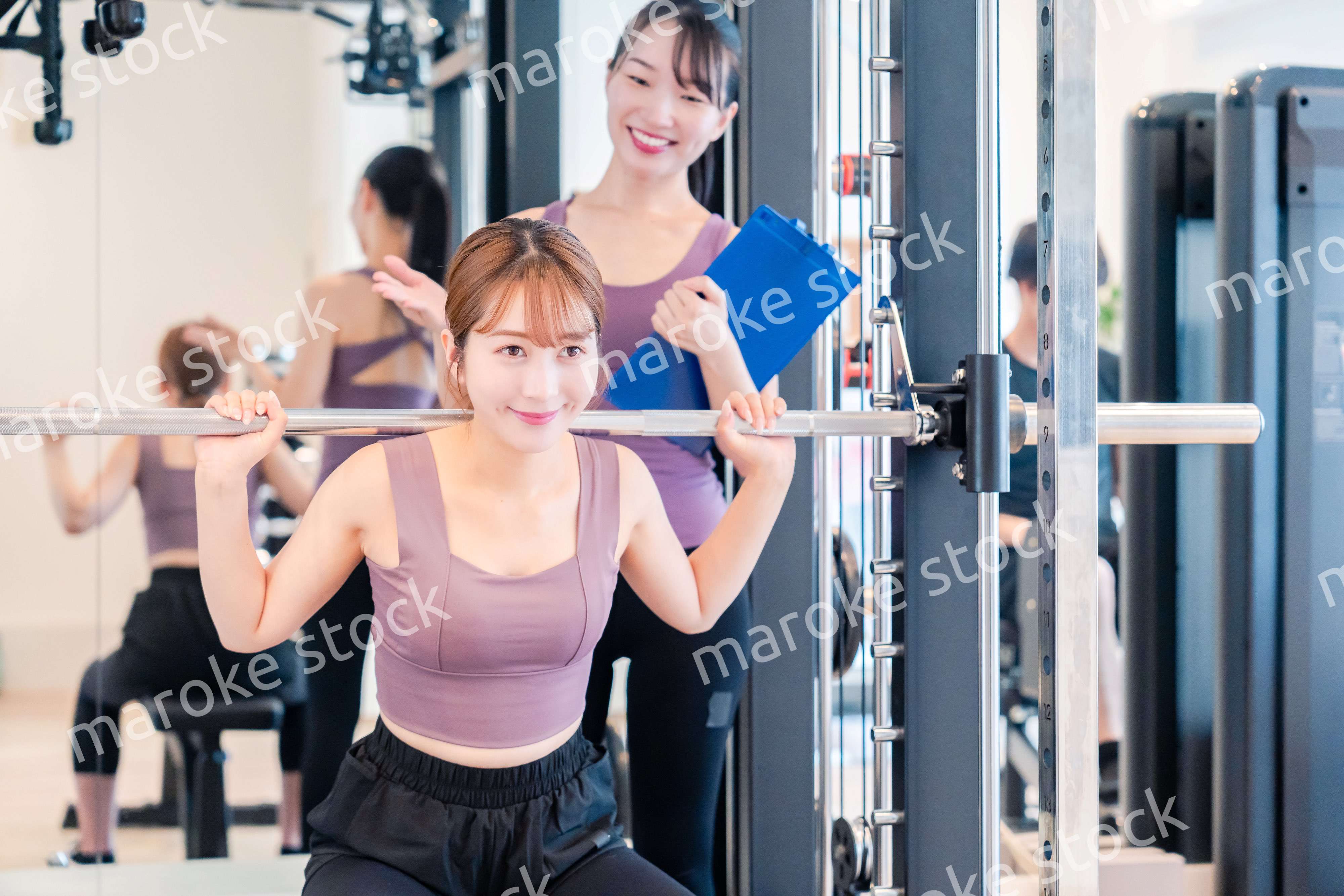 ジムで女性コーチのパーソナルトレーニングを受ける女性