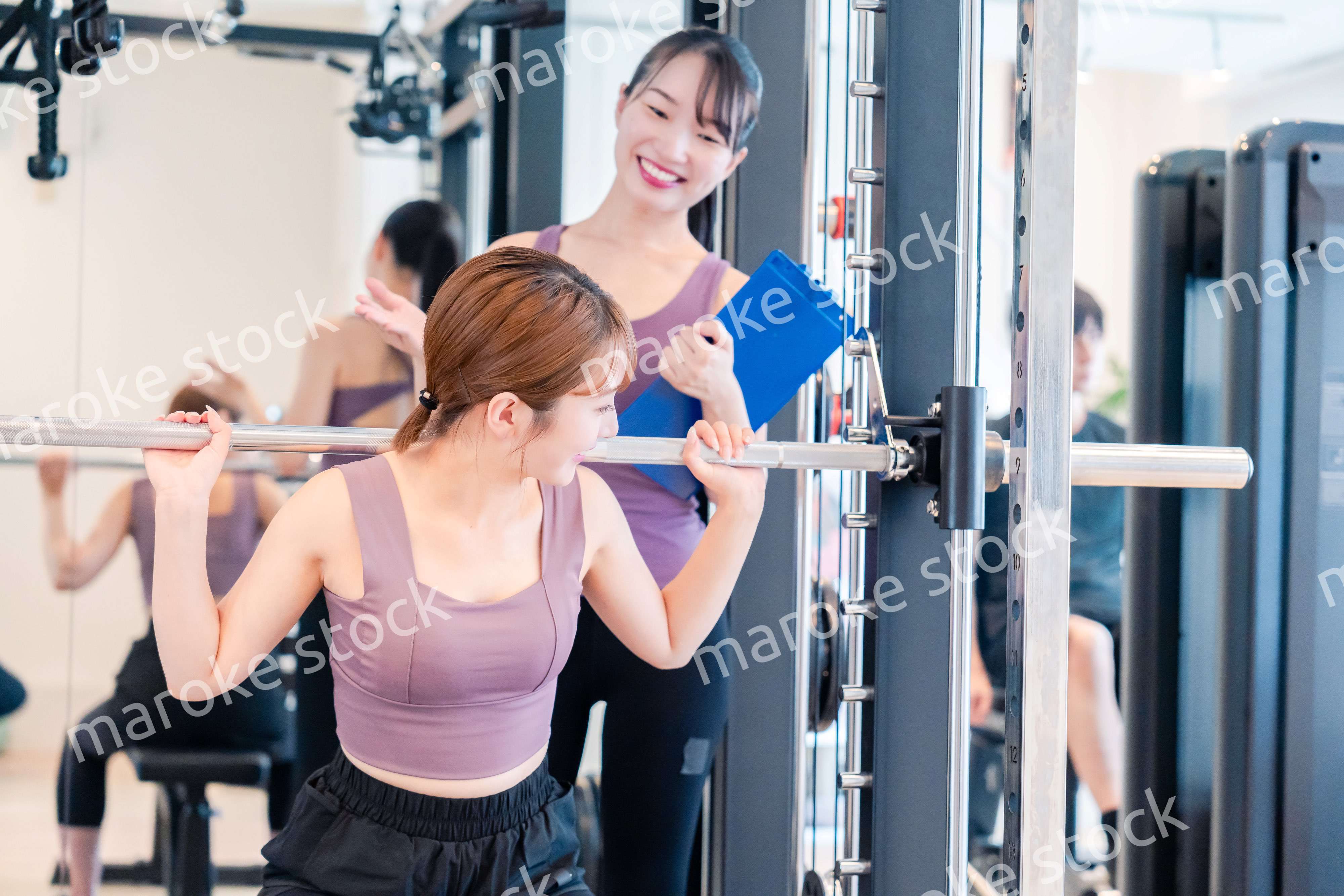ジムで女性コーチのパーソナルトレーニングを受ける女性