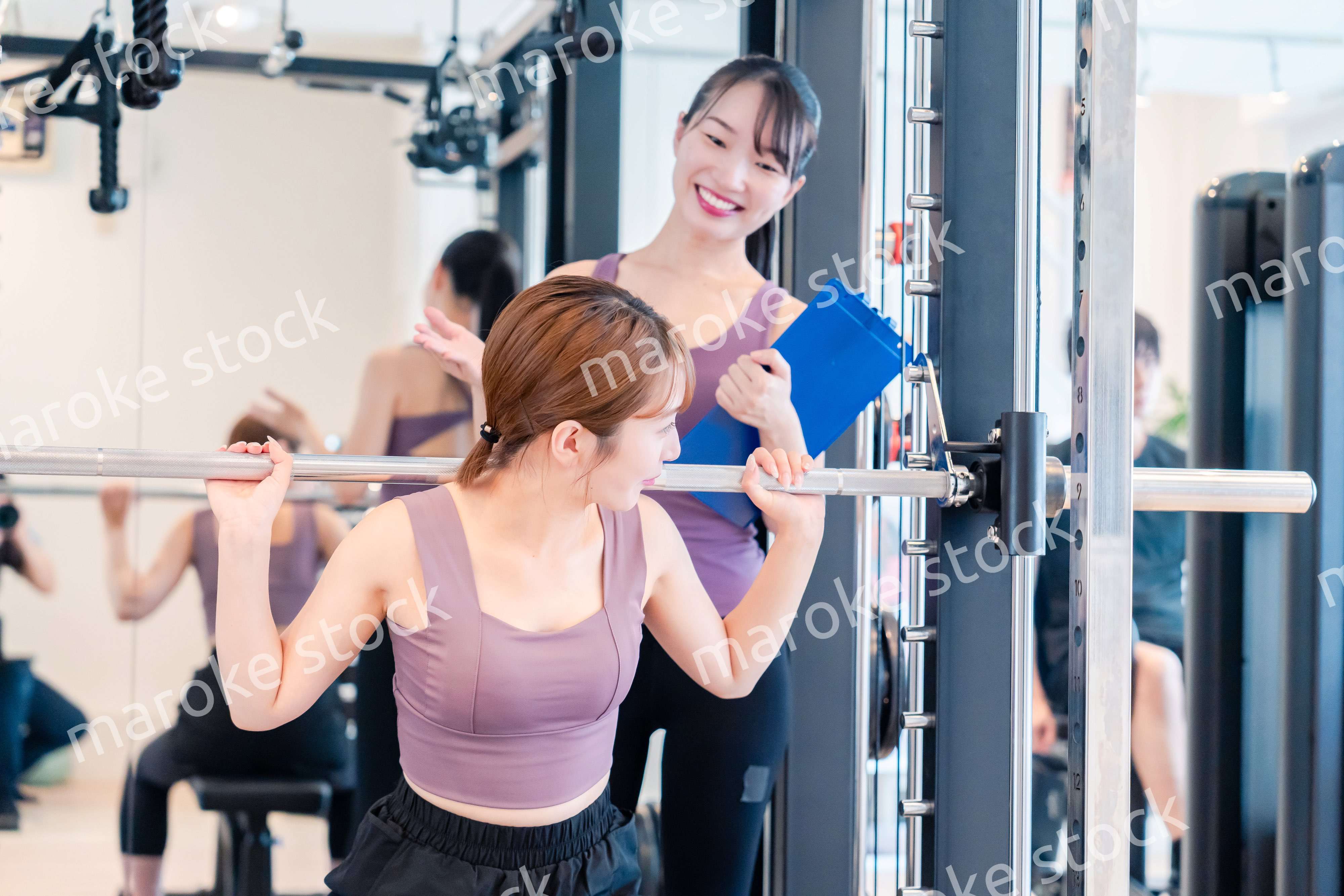 ジムで女性コーチのパーソナルトレーニングを受ける女性