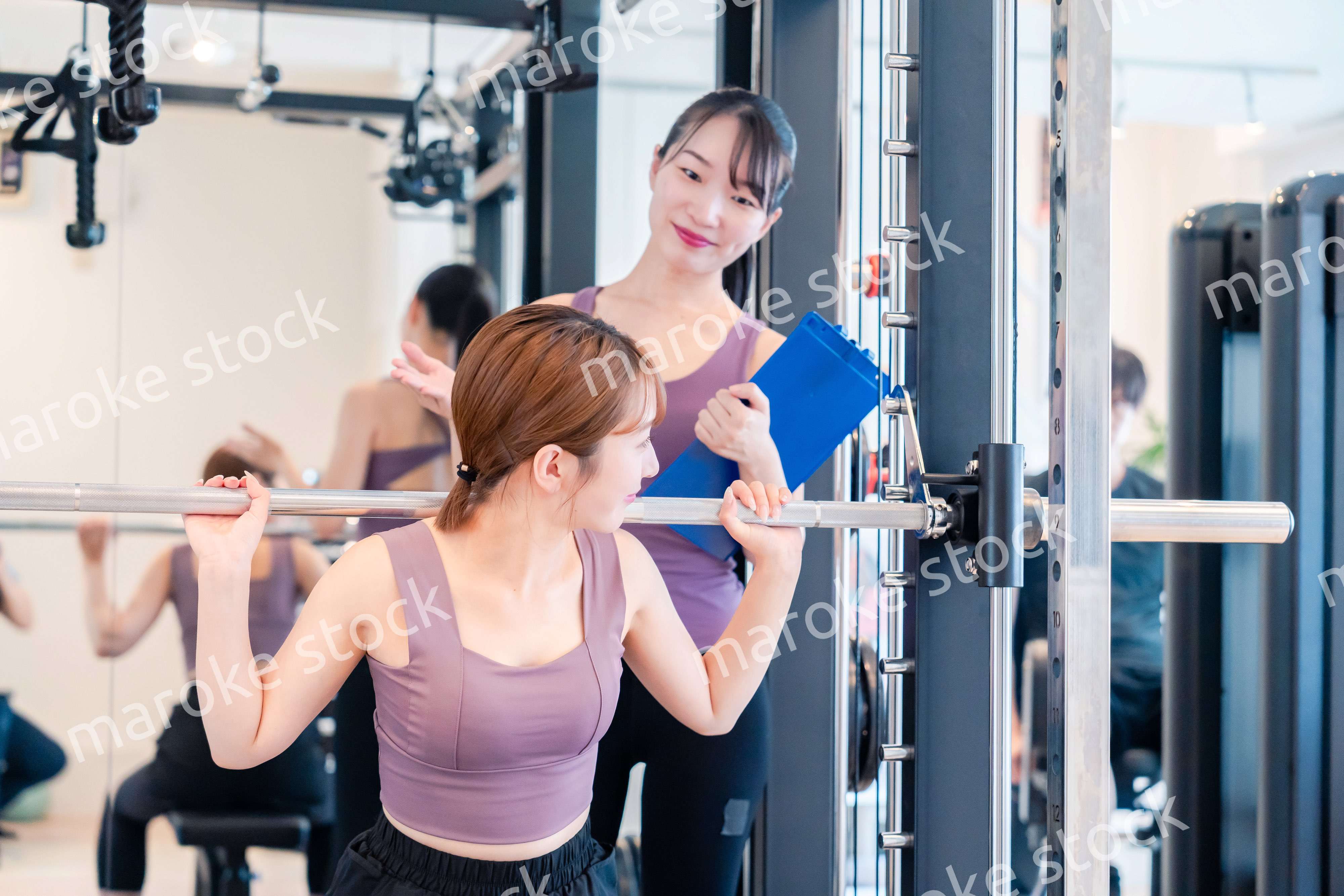 ジムで女性コーチのパーソナルトレーニングを受ける女性