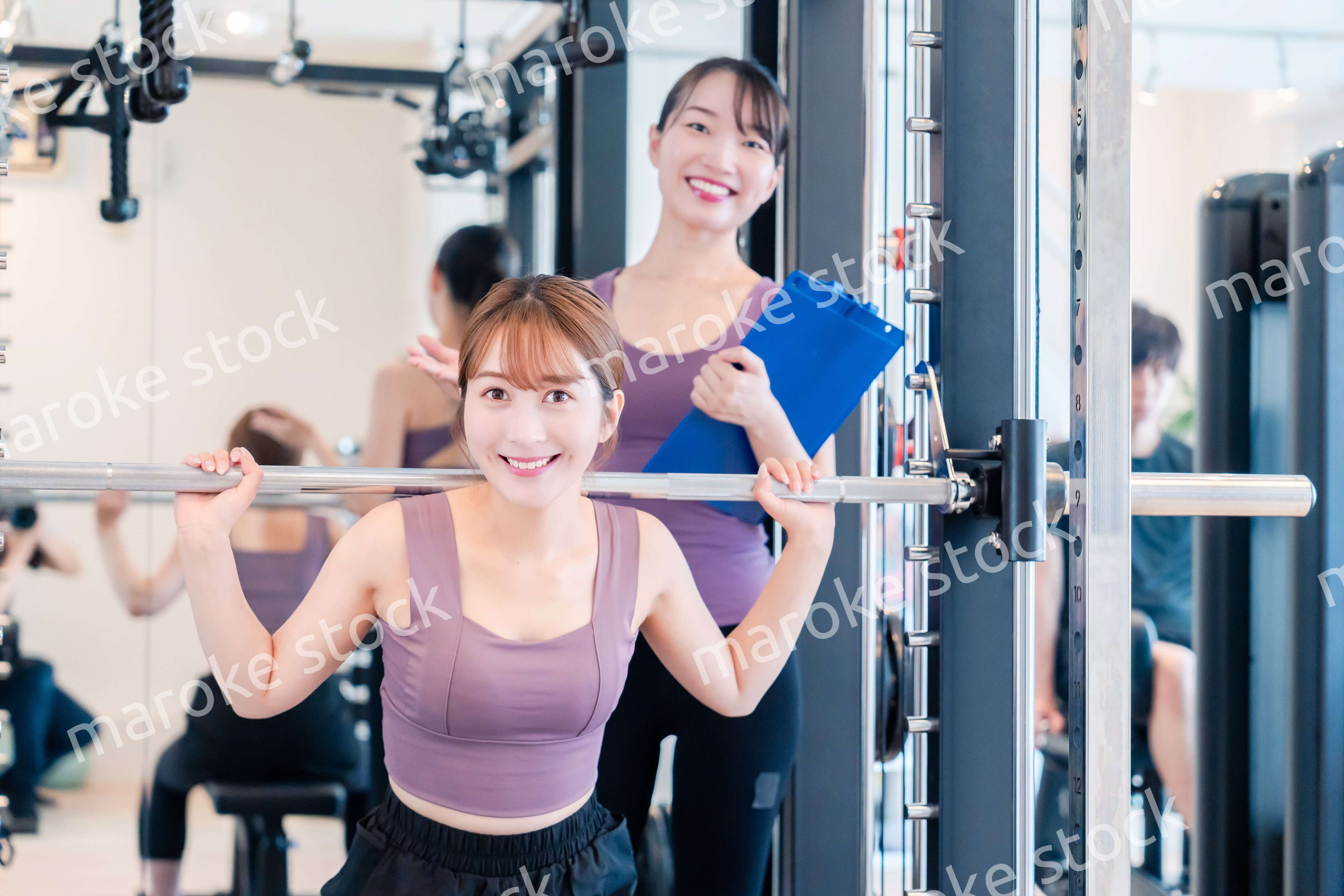 ジムで女性コーチのパーソナルトレーニングを受ける女性