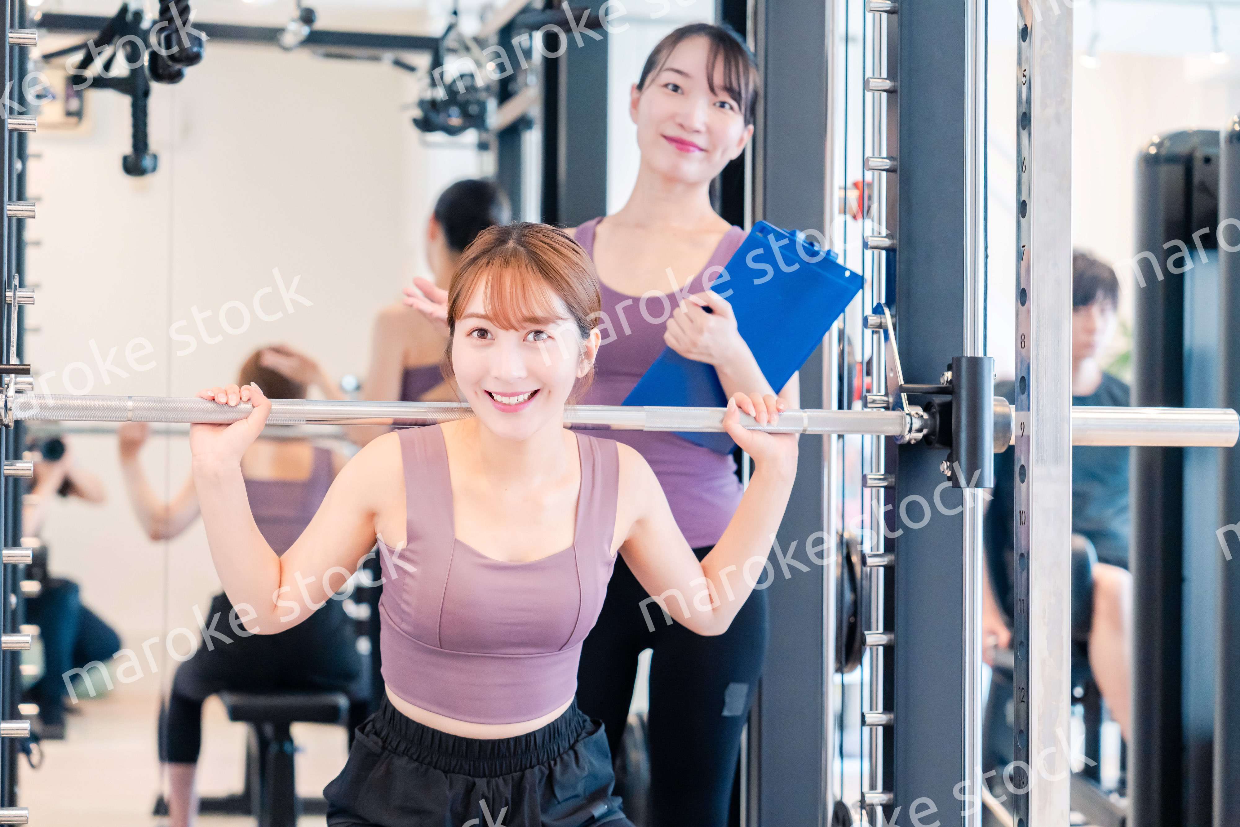 ジムで女性コーチのパーソナルトレーニングを受ける女性