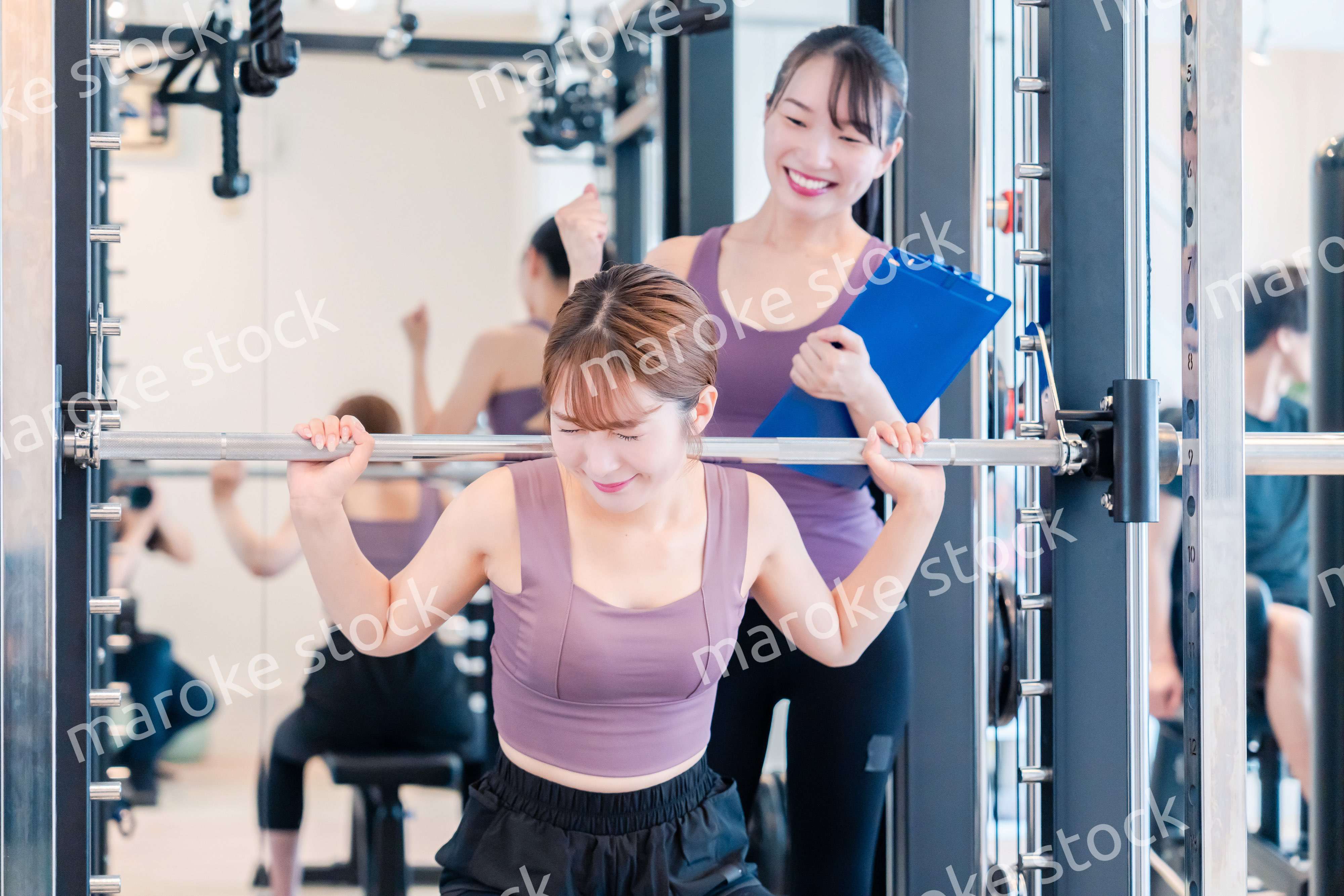 ジムで女性コーチのパーソナルトレーニングを受ける女性