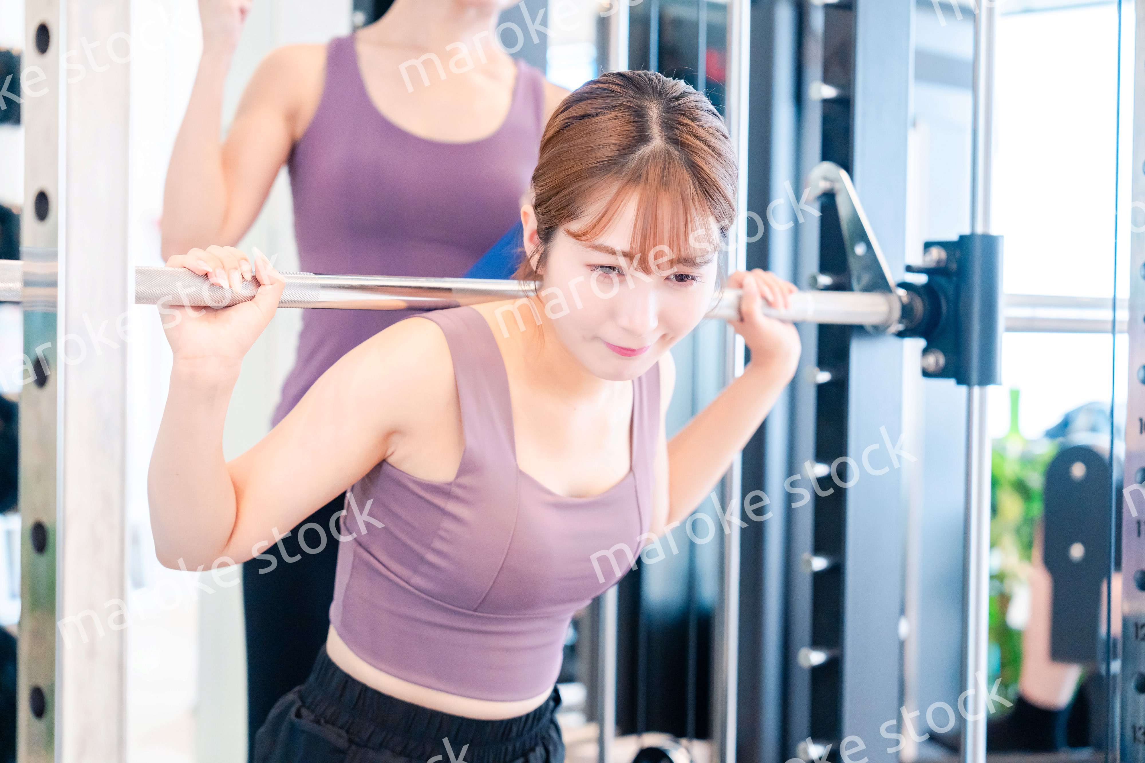 ジムで女性コーチのパーソナルトレーニングを受ける女性