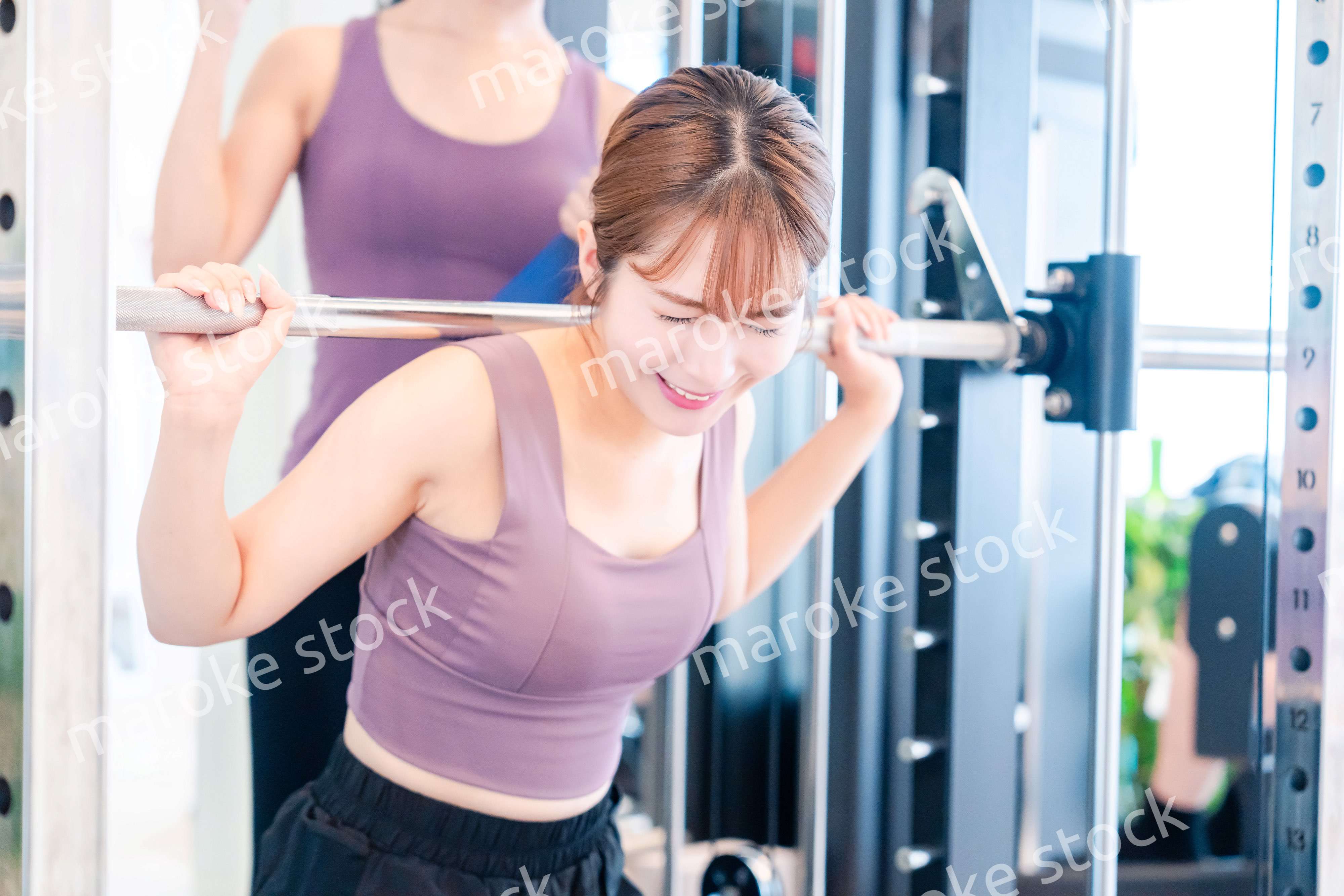 ジムで女性コーチのパーソナルトレーニングを受ける女性