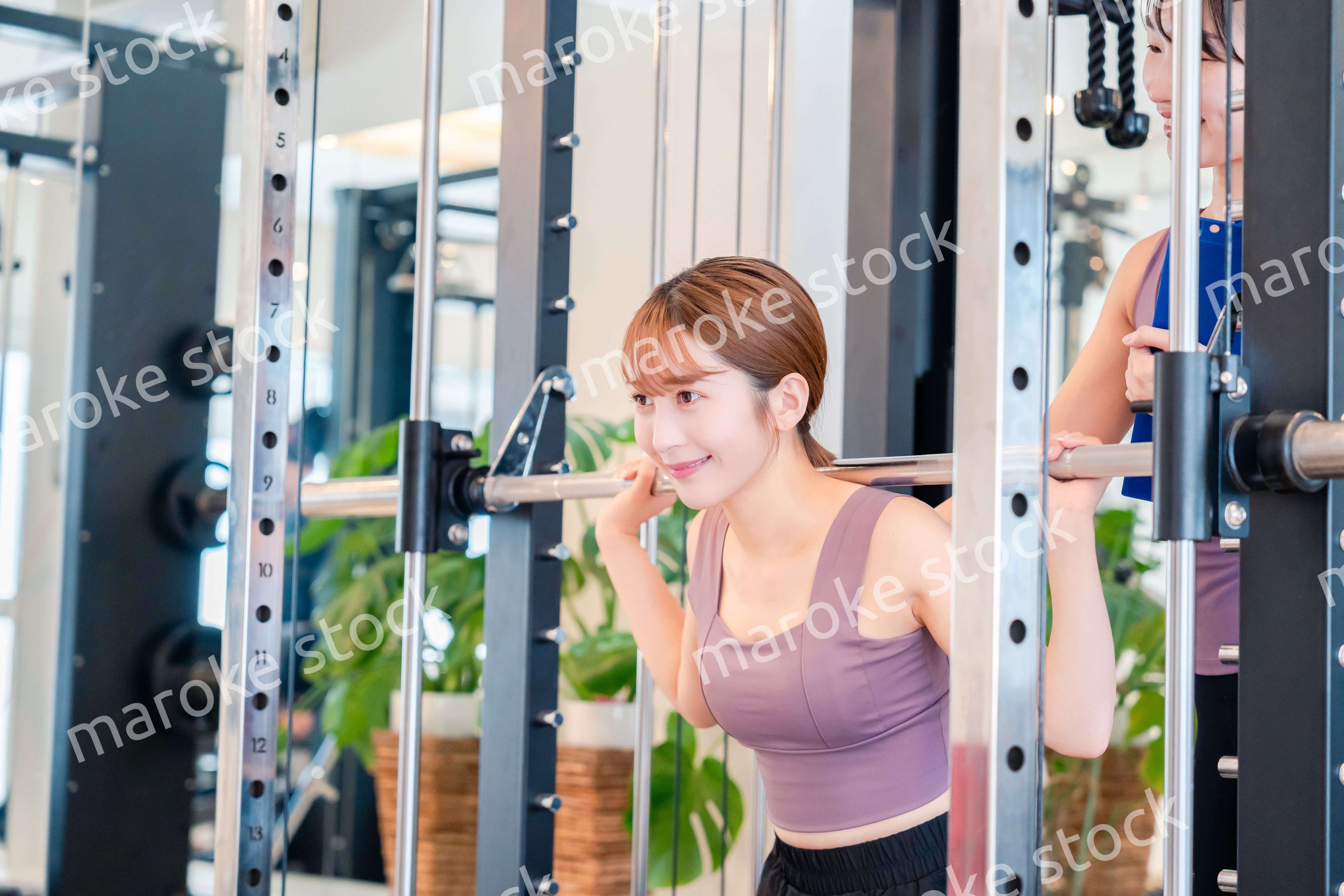 女性トレーナーからの指導を受けて筋トレをする女性