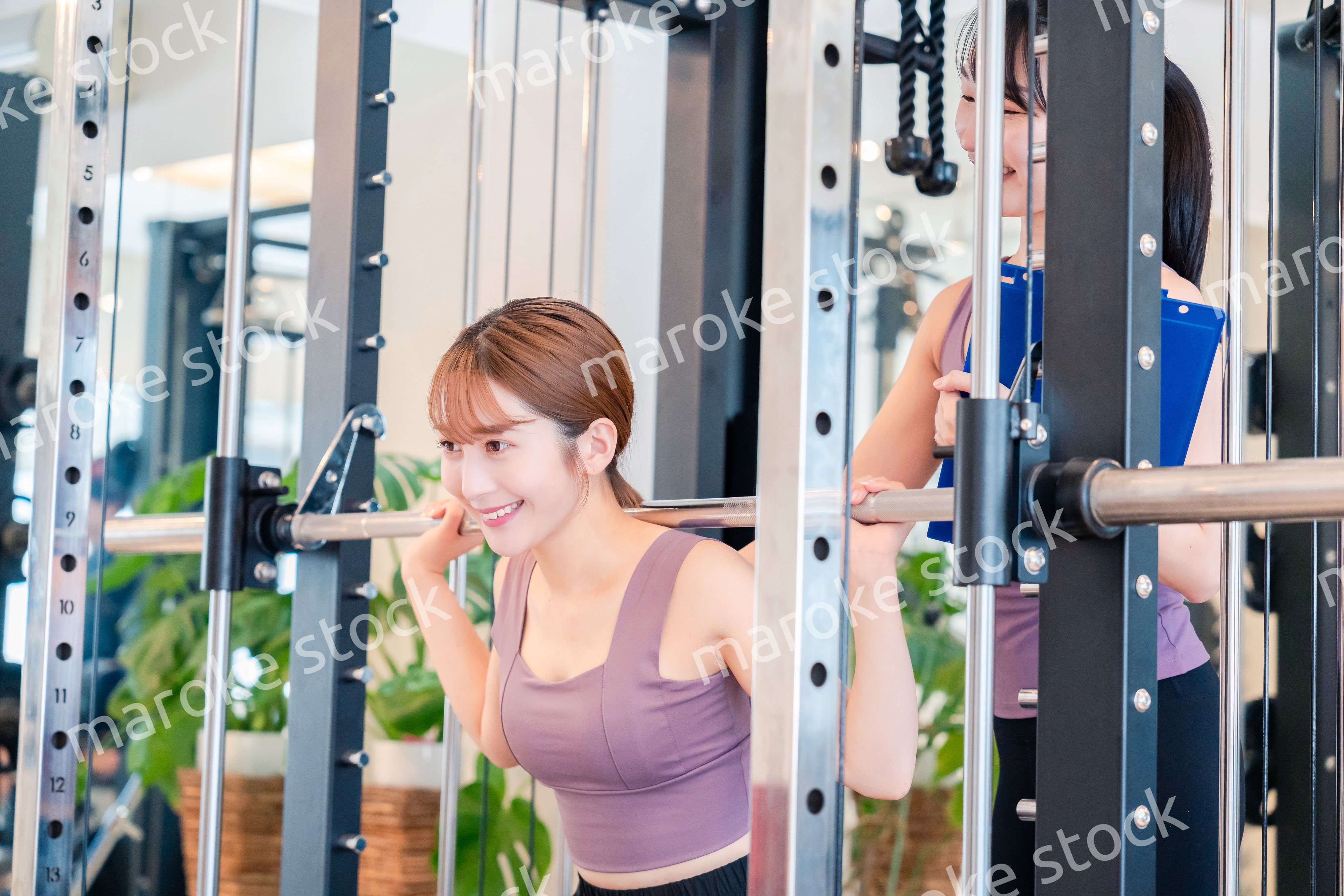 女性トレーナーからの指導を受けて筋トレをする女性