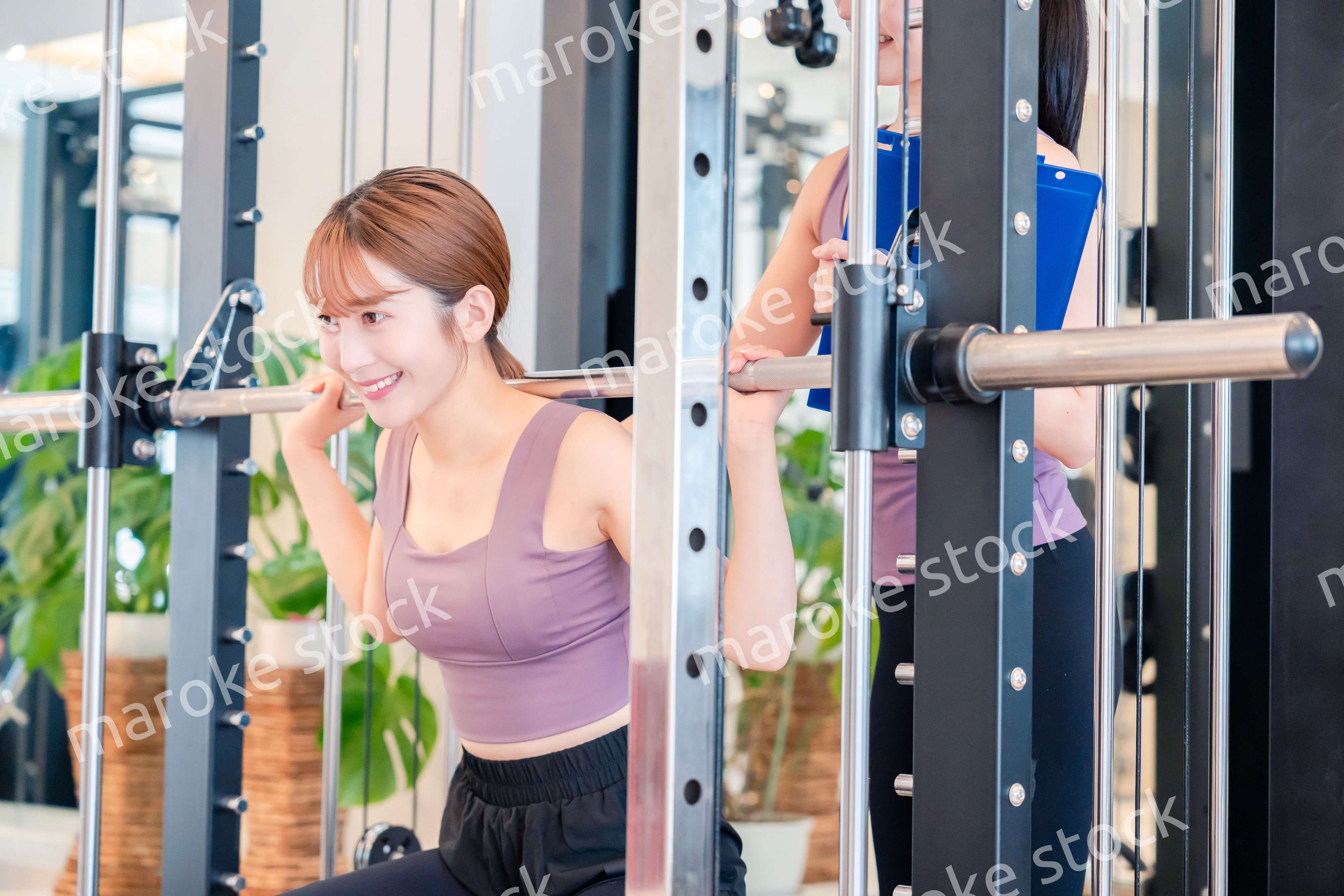 女性トレーナーからの指導を受けて筋トレをする女性