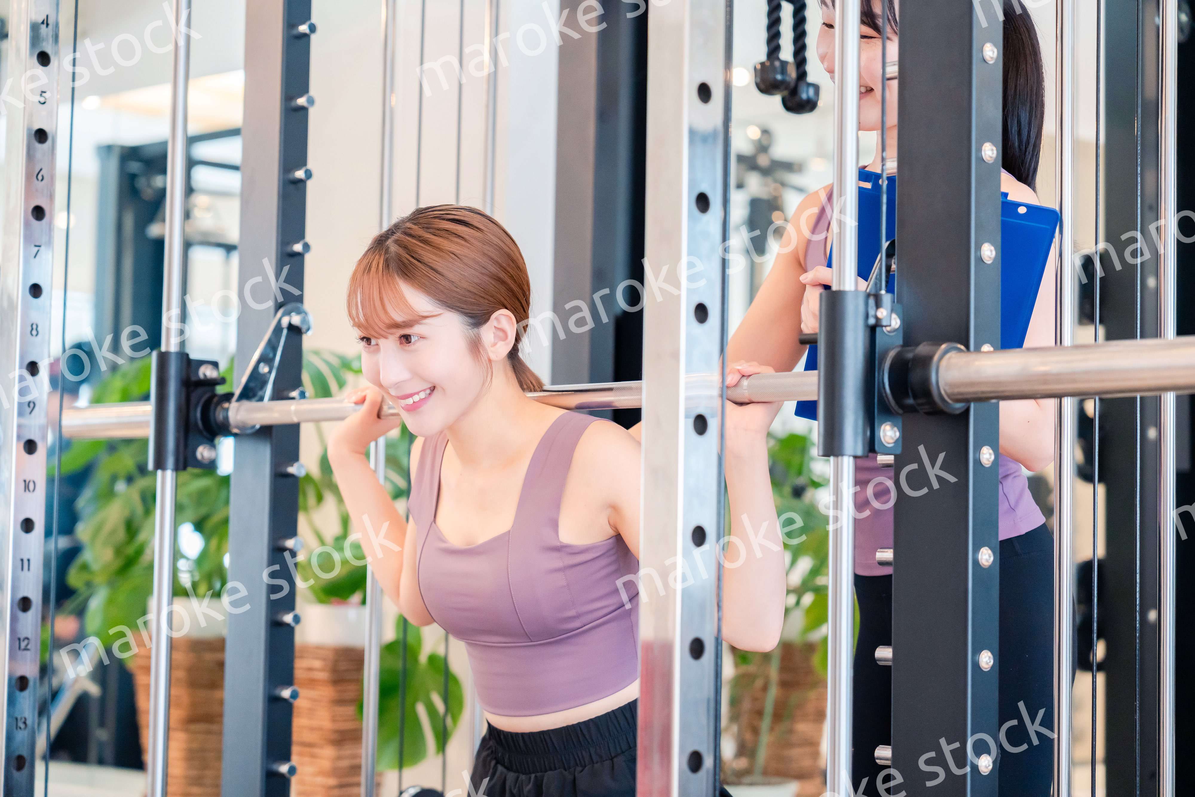 女性トレーナーからの指導を受けて筋トレをする女性