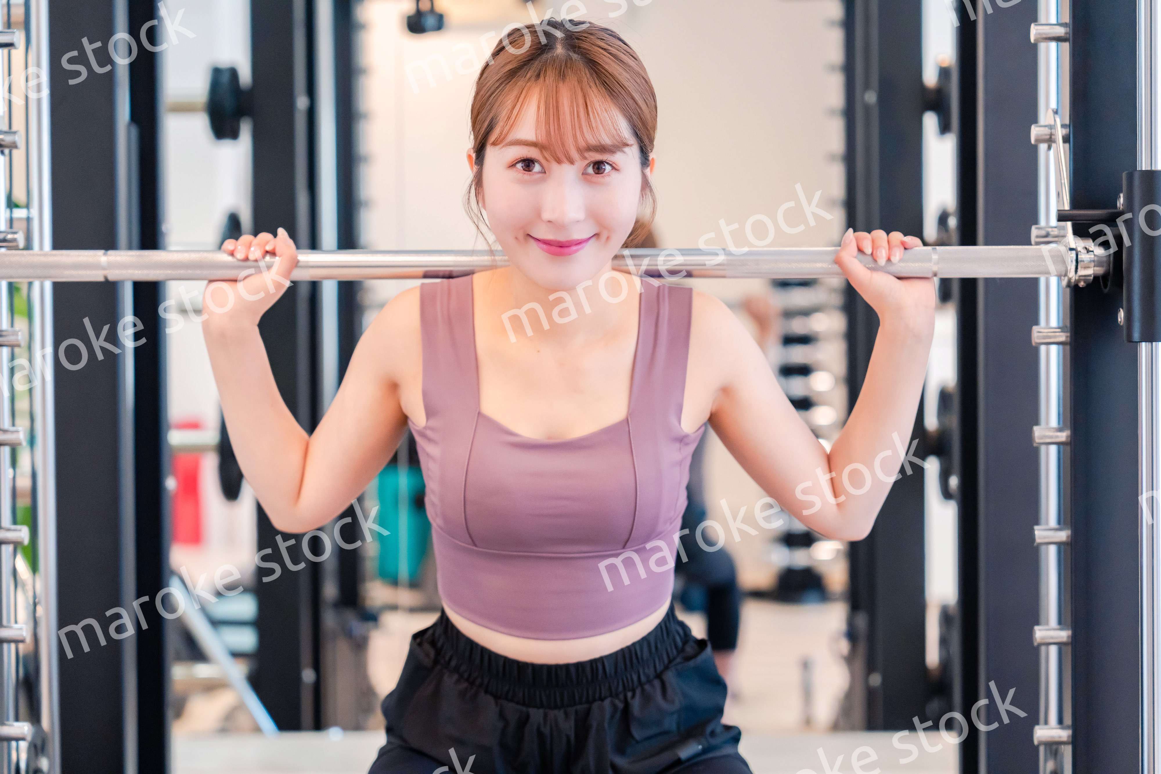 ジムで筋トレをするスポーティーな若い女性