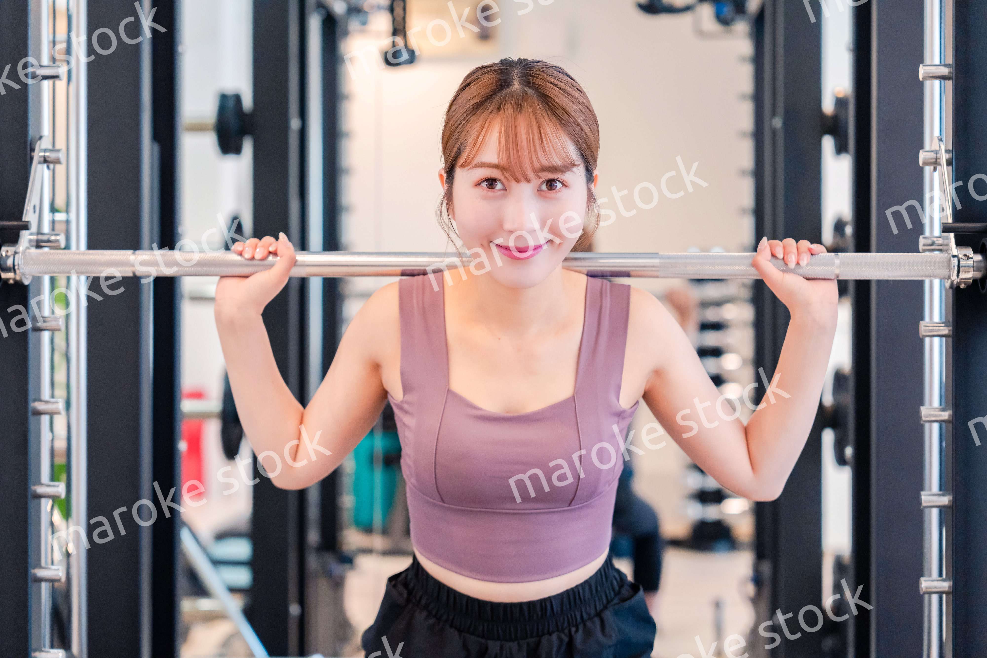 ジムで筋トレをするスポーティーな若い女性