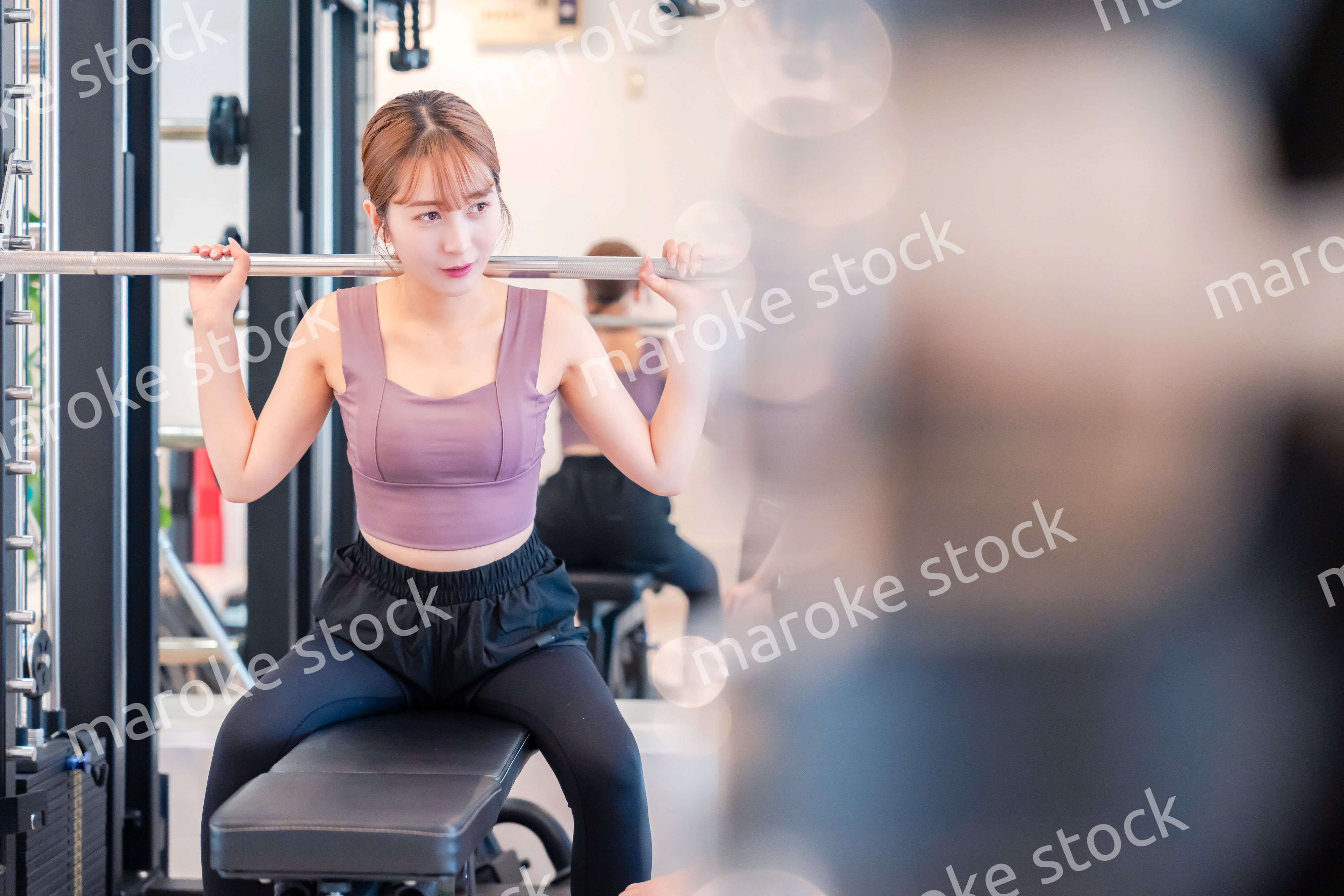 ジムで筋トレをするスポーティーな若い女性