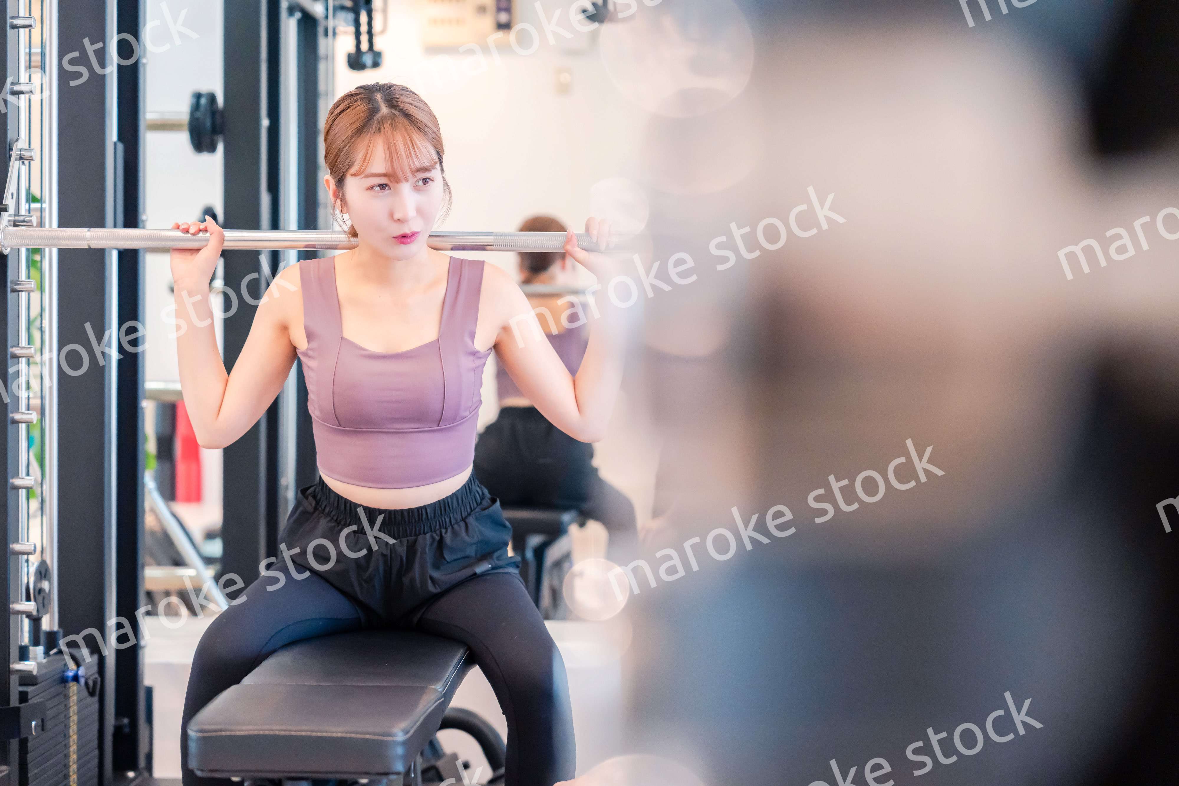 ジムで筋トレをするスポーティーな若い女性