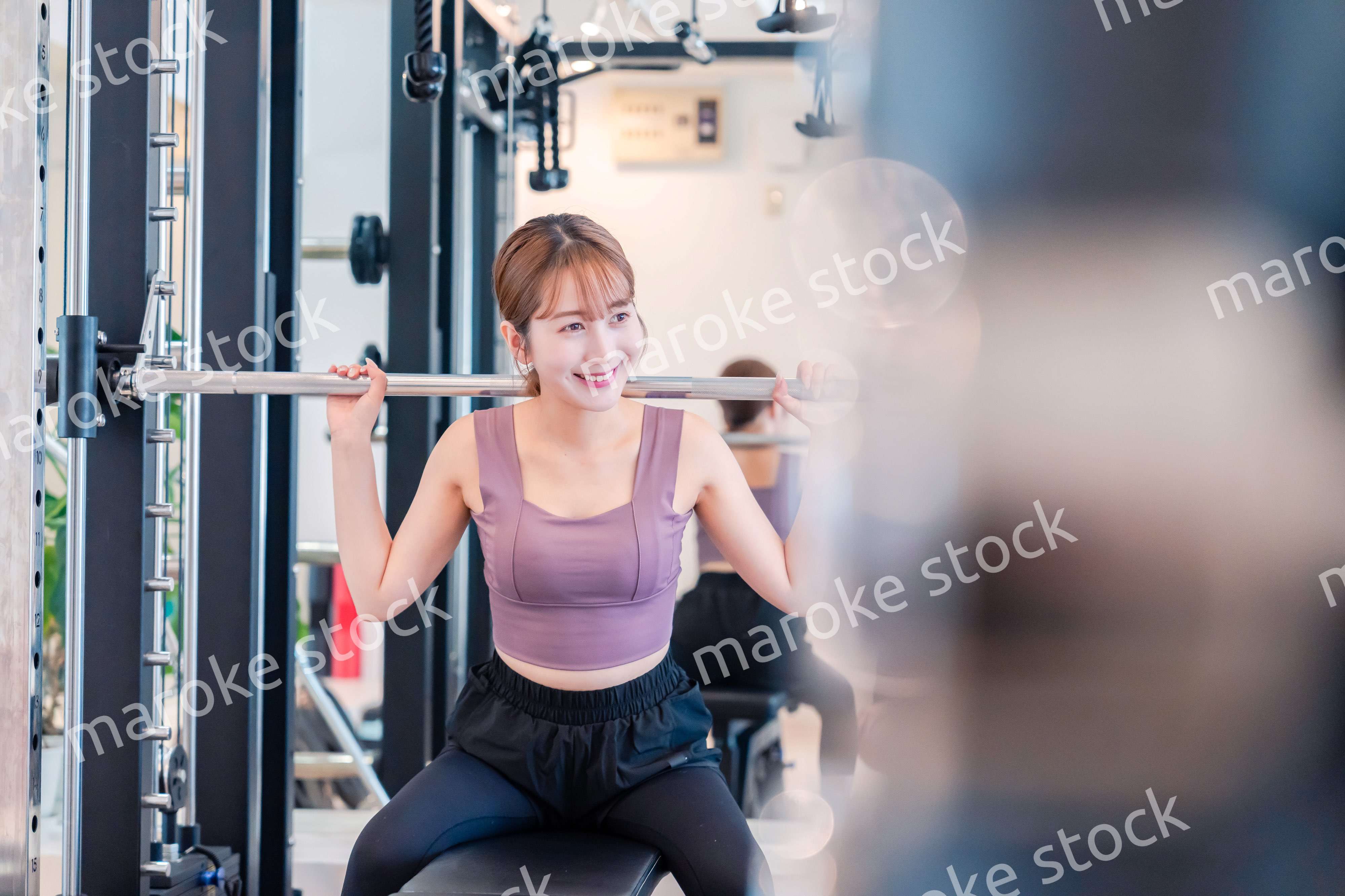 ジムで筋トレをするスポーティーな若い女性