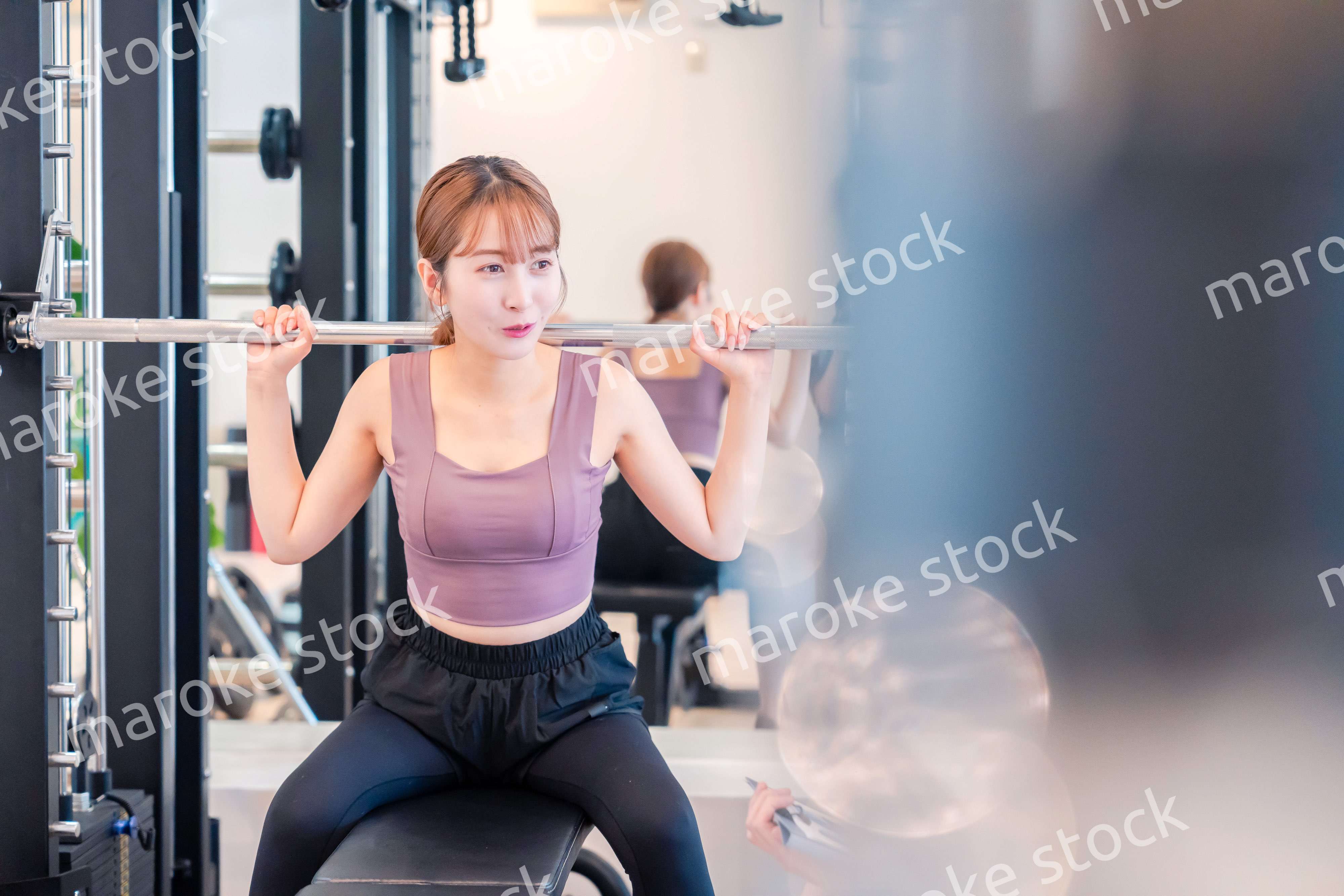 ジムで筋トレをするスポーティーな若い女性