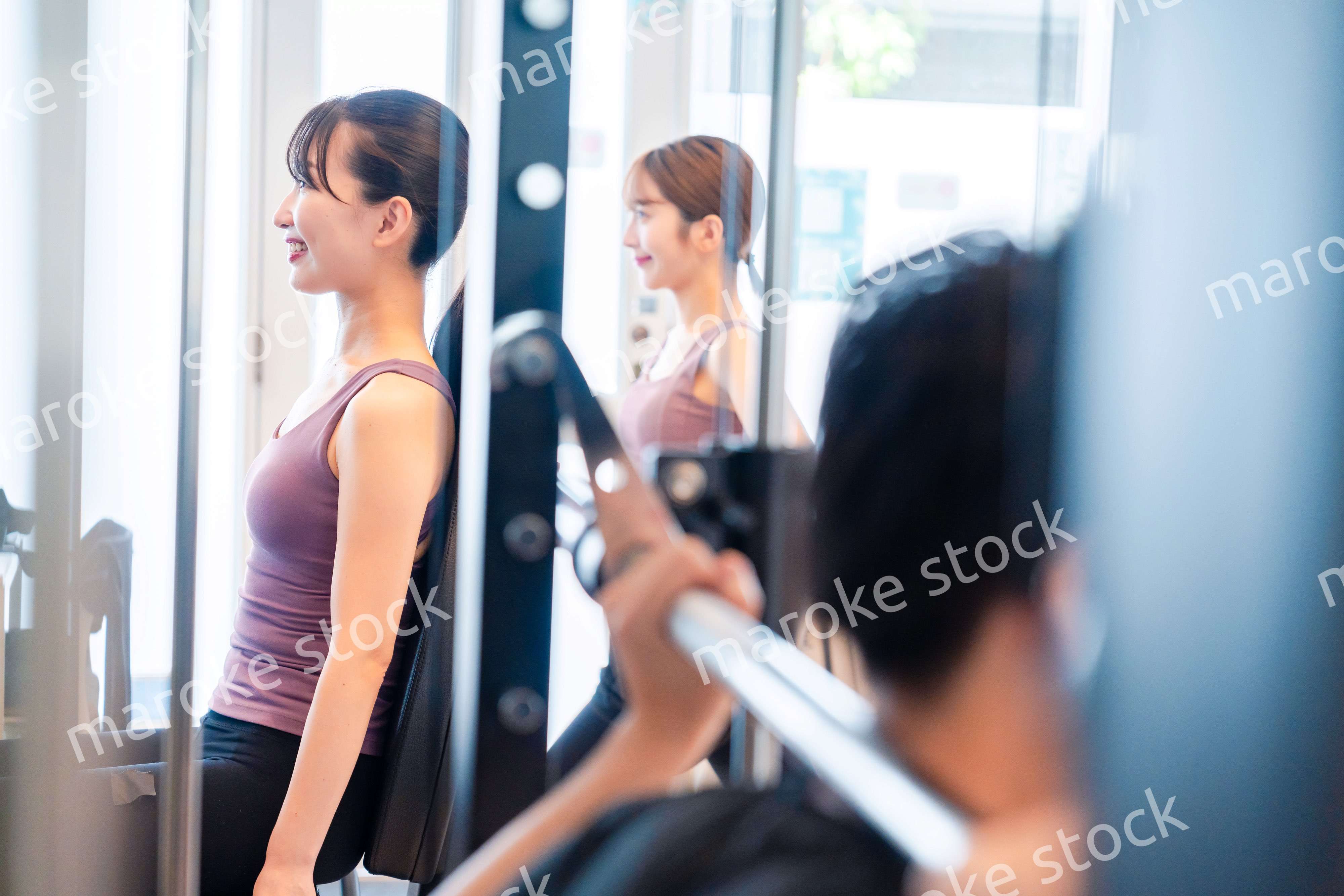 ジムのマシーンでトレーニングをする人