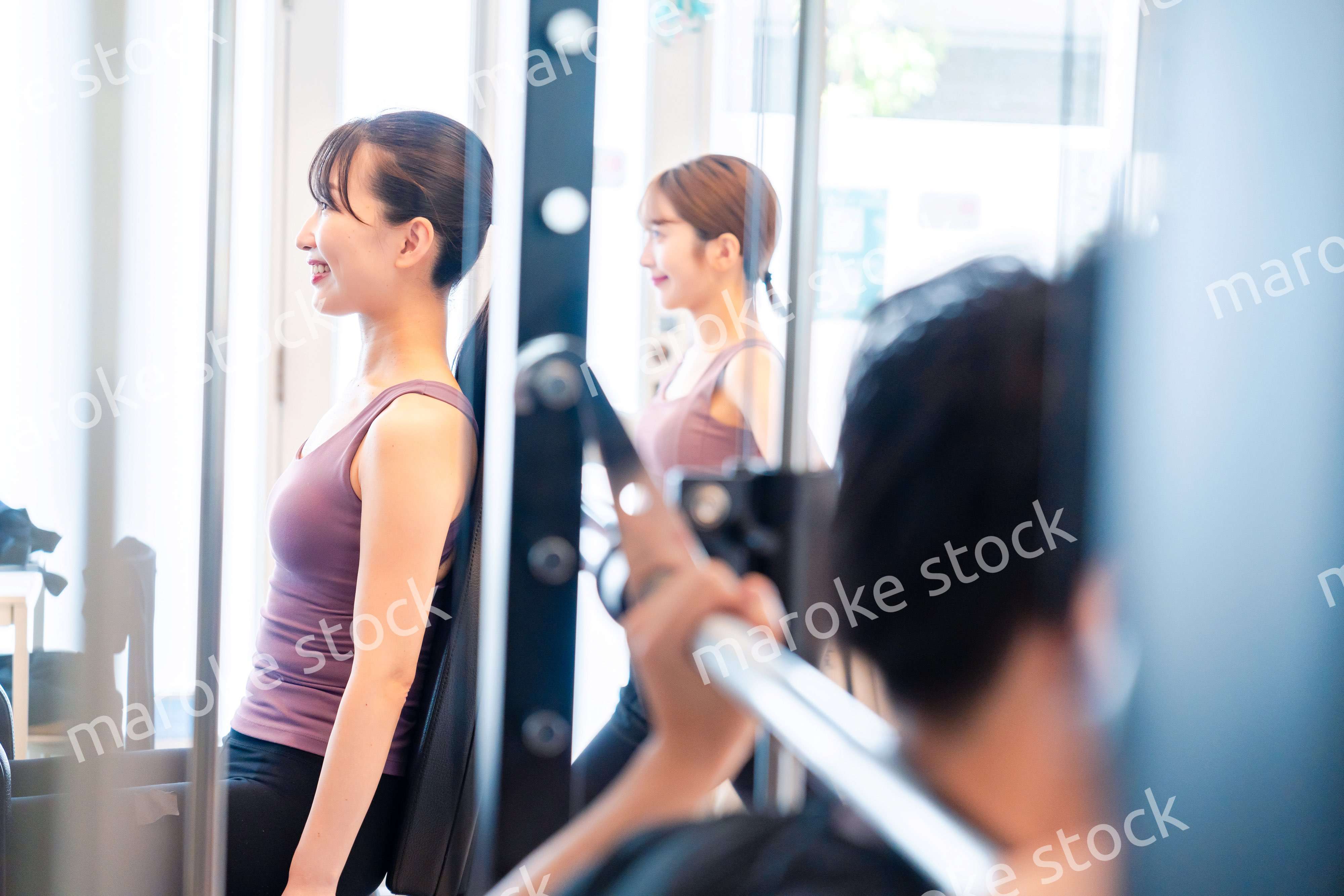 ジムのマシーンでトレーニングをする人