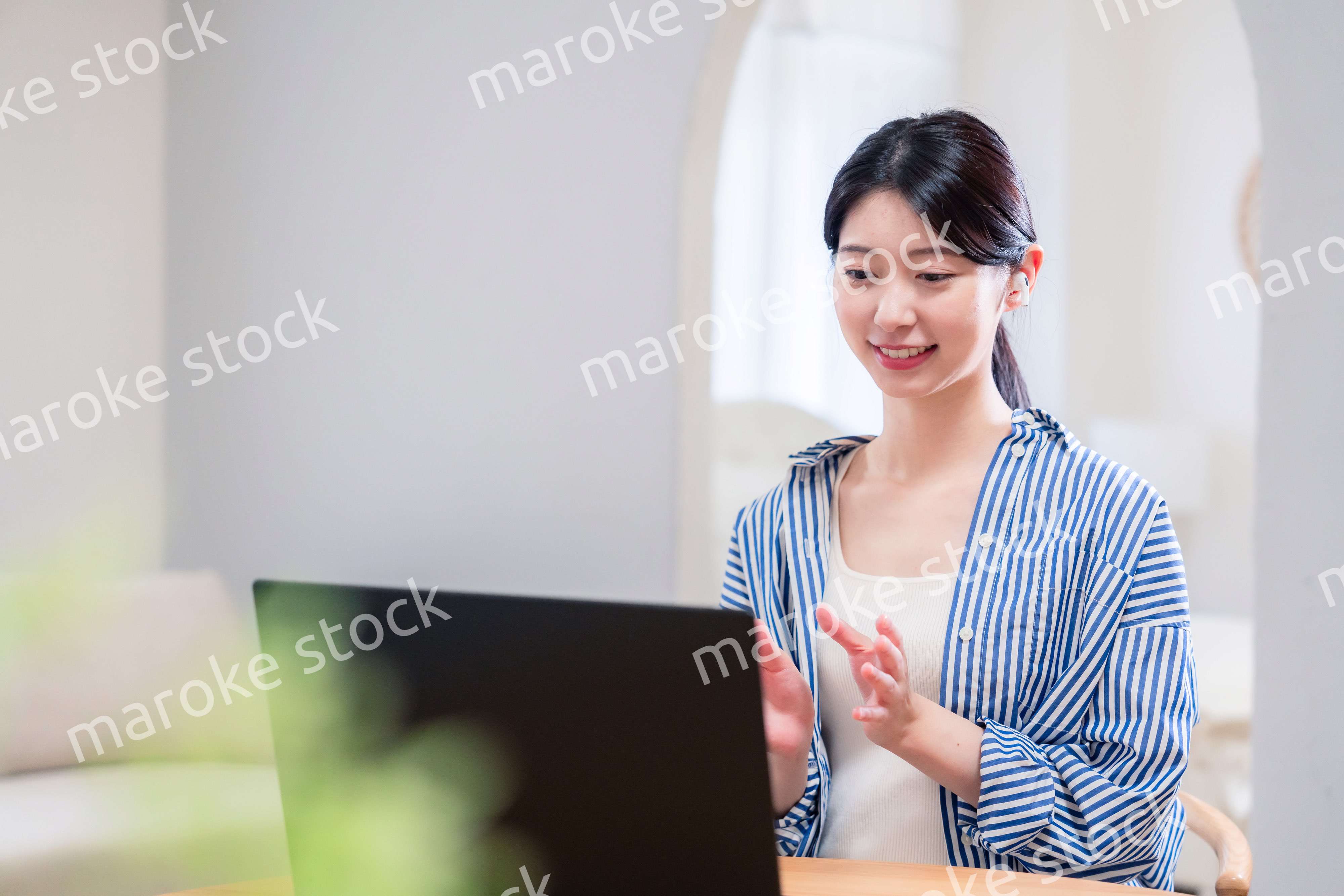 在宅でリモート会議に参加する若い女性社員