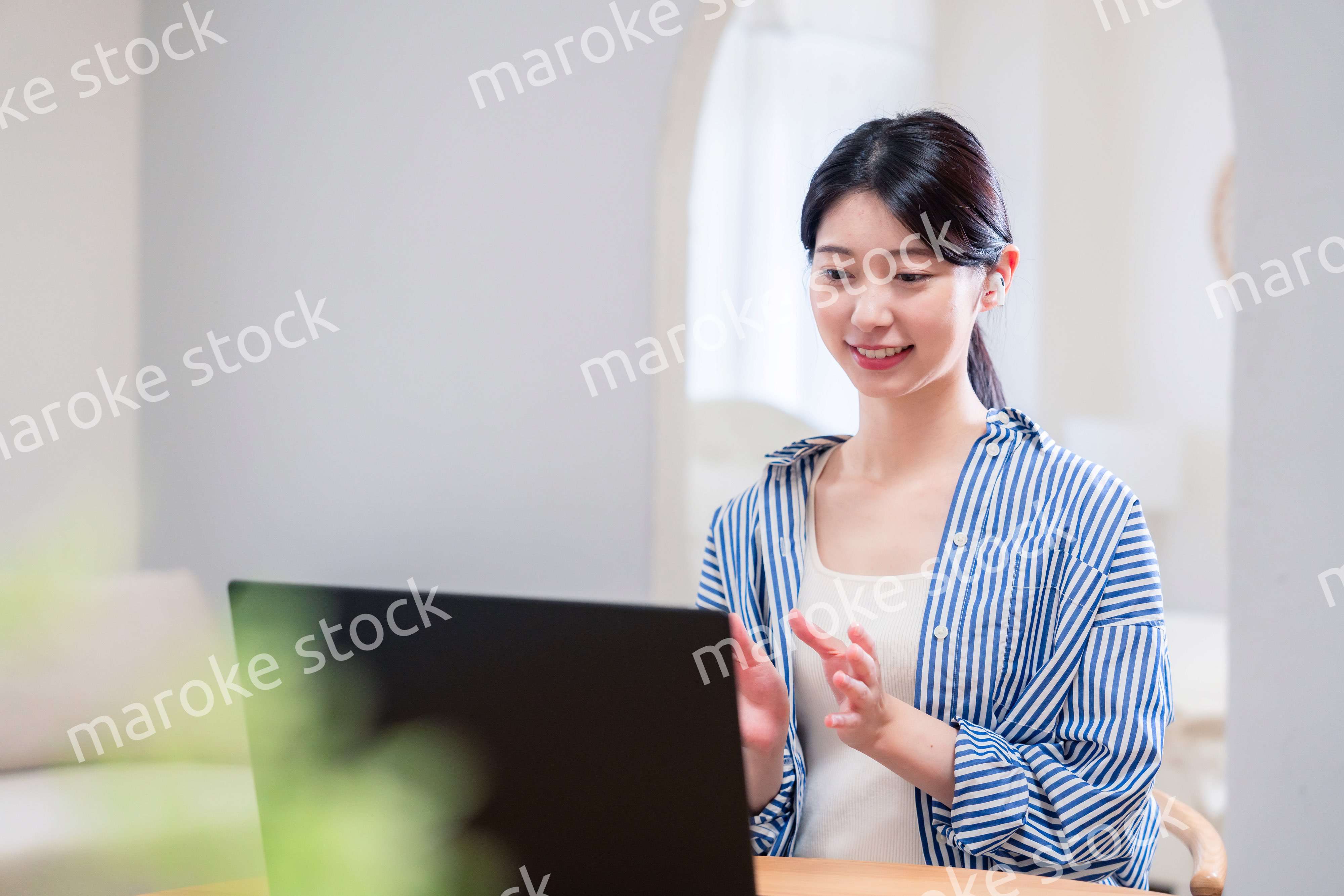 在宅でリモート会議に参加する若い女性社員